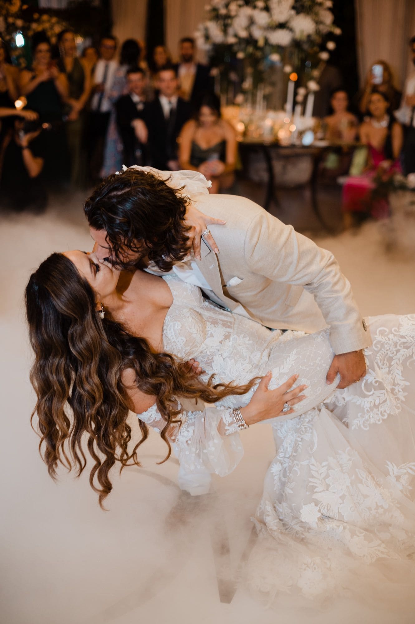 Groom dips the bride into a dramatic kiss as guests watch from candlelit tables during the first dance at Hotel Pensativo.