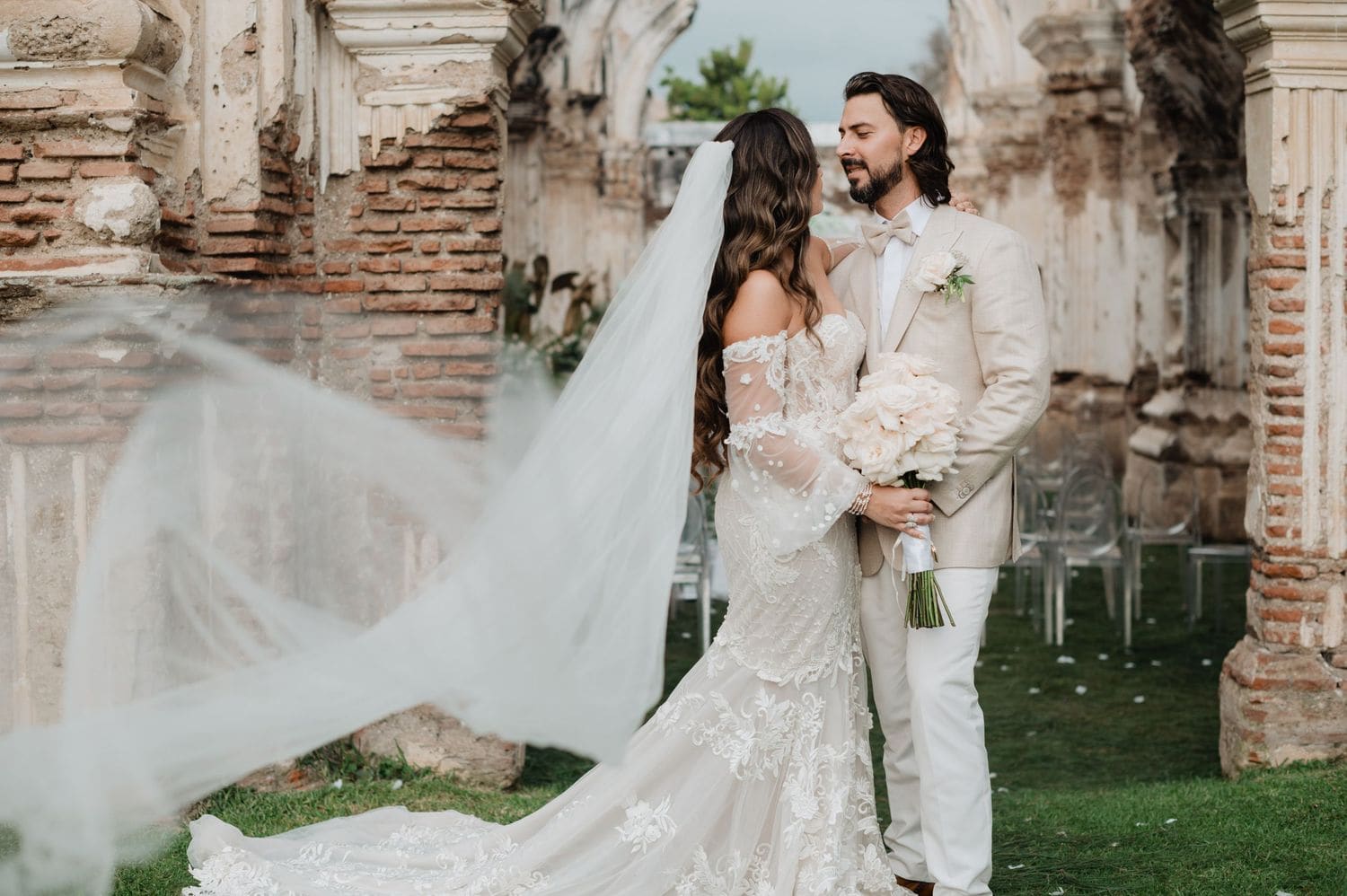 Veil swirls in the foreground as Marite + Rudy embrace among the brick ruins of Antigua Guatemala.