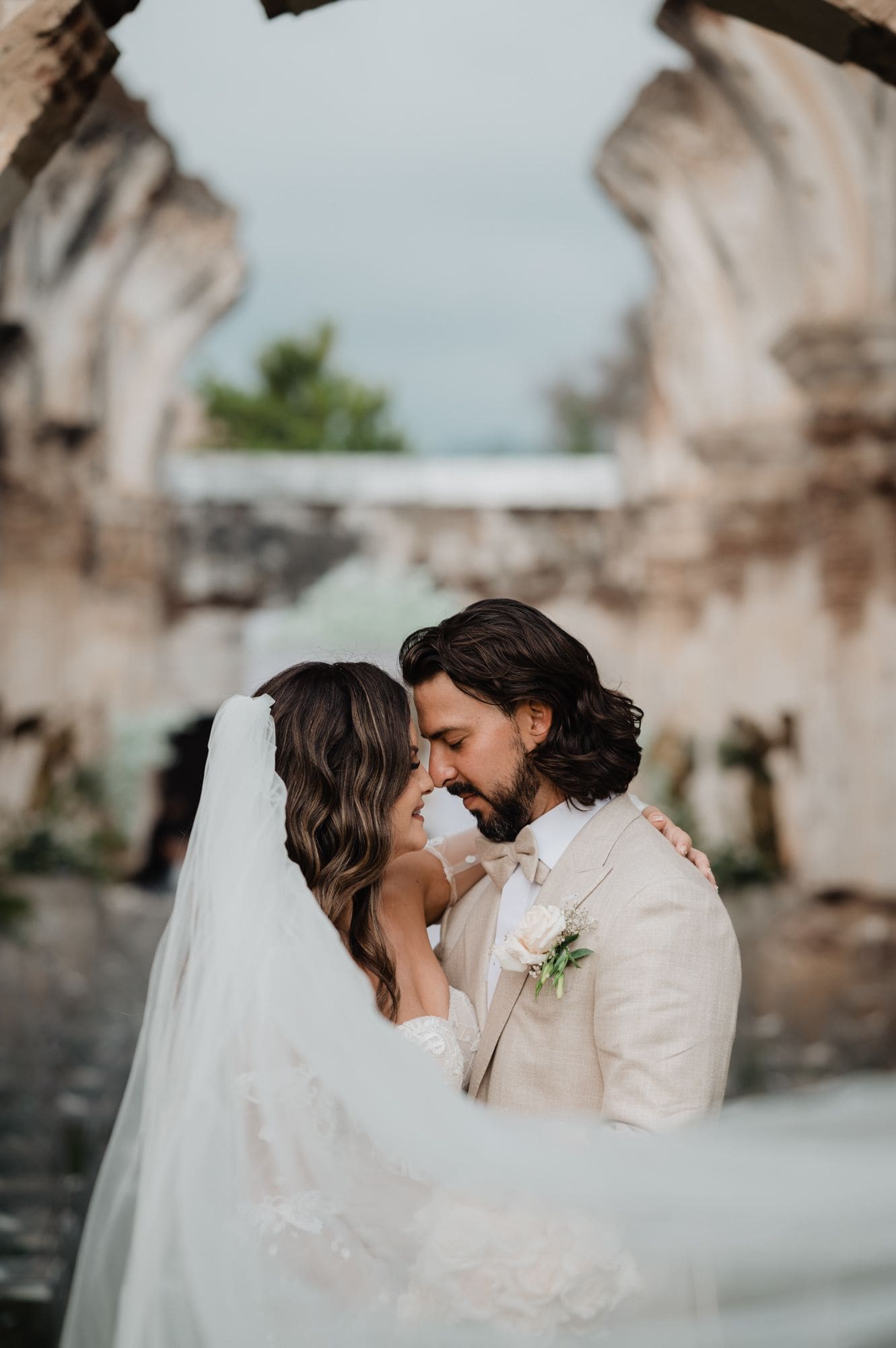 Intimate close-up of the couple's foreheads touching framed by a soft-focus ruin arch at Casa de la Ruina.