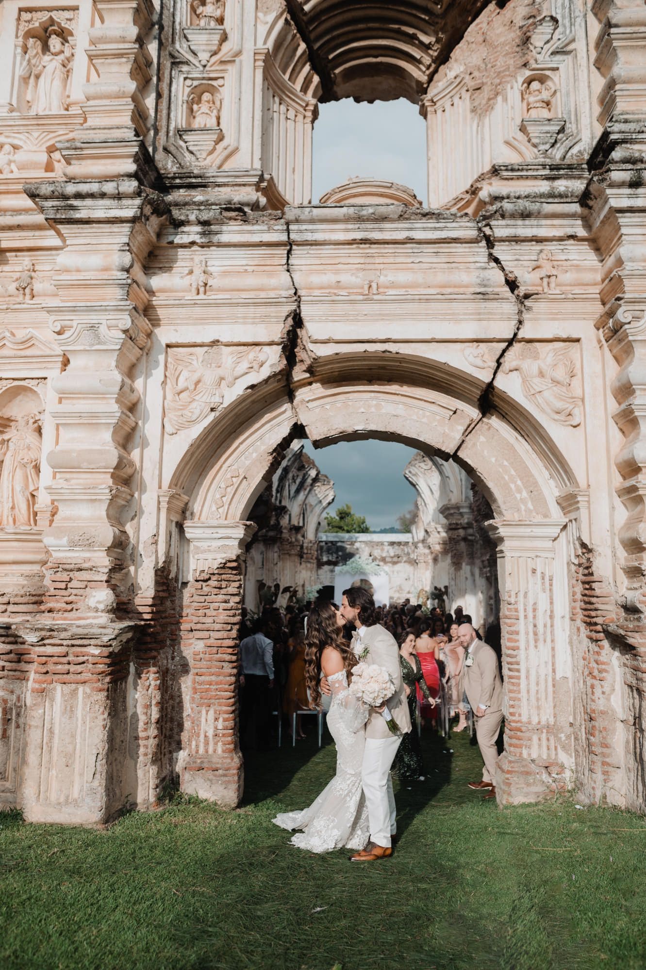 Newlyweds share a kiss framed by two stacked ruin arches just after the ceremony at Casa de la Ruina.