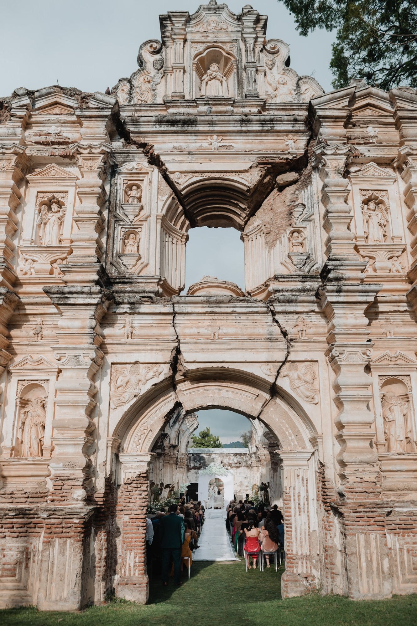 Sculpted baroque facade of Casa de la Ruina cracked open to reveal the ceremony aisle and altar inside the colonial ruin.