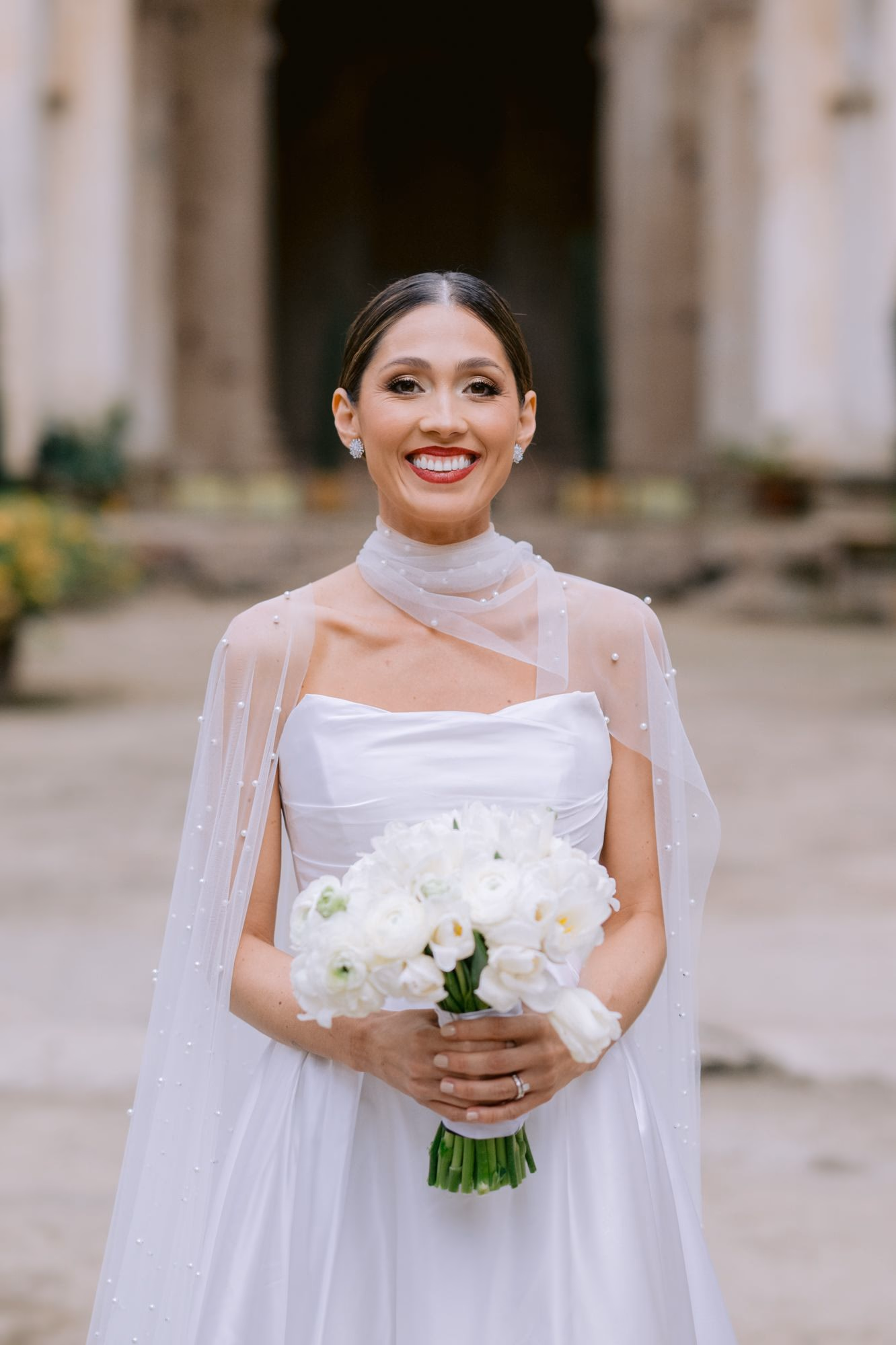 Bride in sheer cape dress with white bouquet