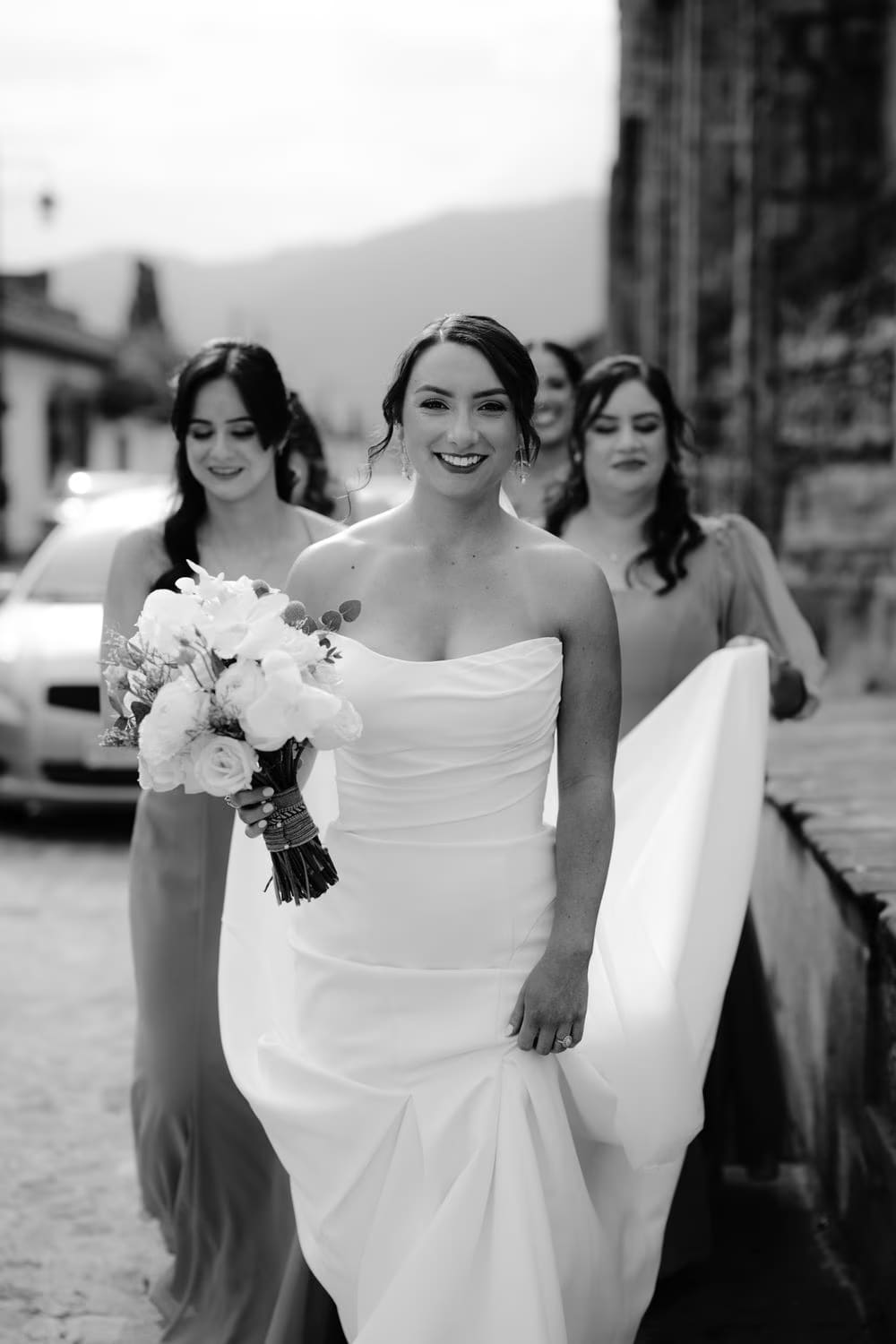 Bride leads her bridesmaids in mustard-yellow gowns down a cobblestone street toward the ceremony venue in Antigua Guatemala.