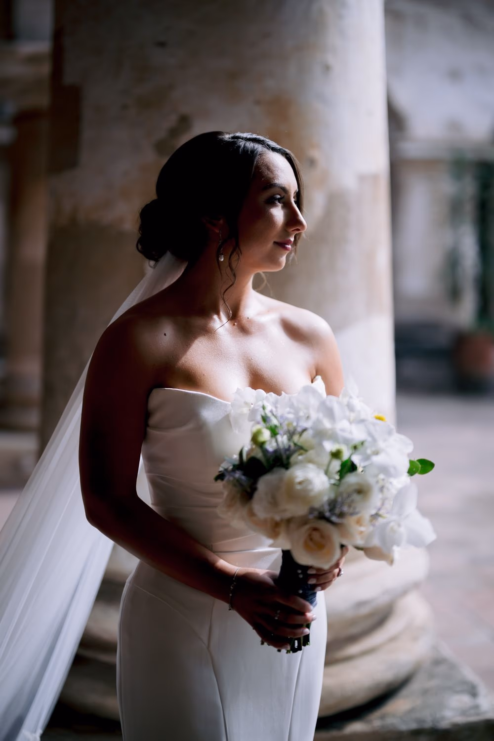 Black-and-white candid of the smiling bride walking with her bridesmaids close behind, bouquet in hand.