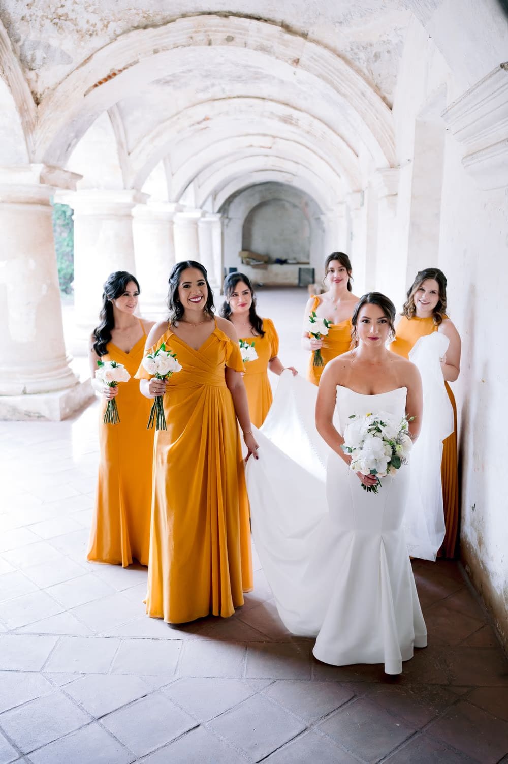 Wide view of the wedding ceremony setup on the lawn of Capuchinas Ruins, guests seated before the floral arch and volcano horizon.