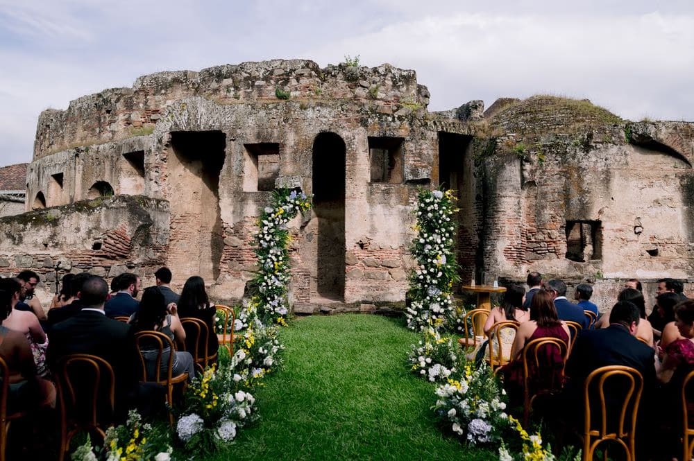 Bride leads her bridesmaids in mustard gowns beneath the vaulted arches of the convent cloister.