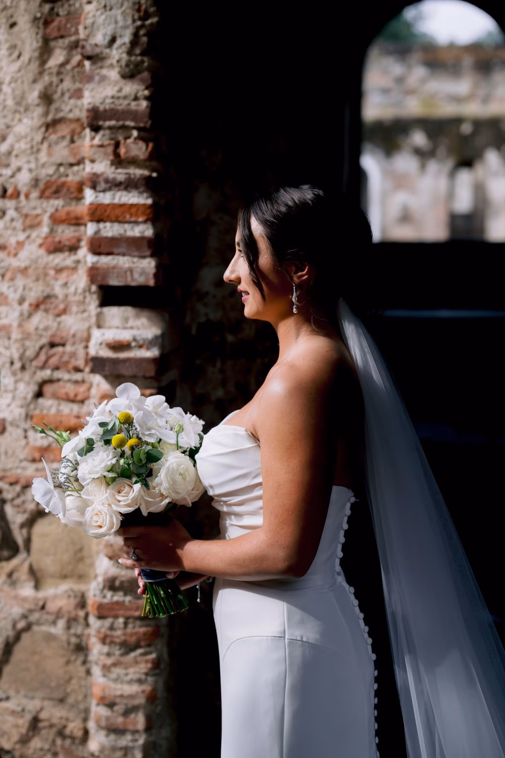 Guests sit beneath the towering ruined walls as the floral aisle leads toward the ceremony arch — outdoor destination wedding at Capuchinas Ruins.