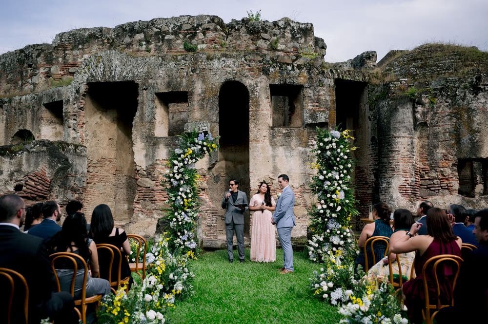 Side bridal portrait against a brick-and-plaster archway, the bride's veil grazing the warm stone.
