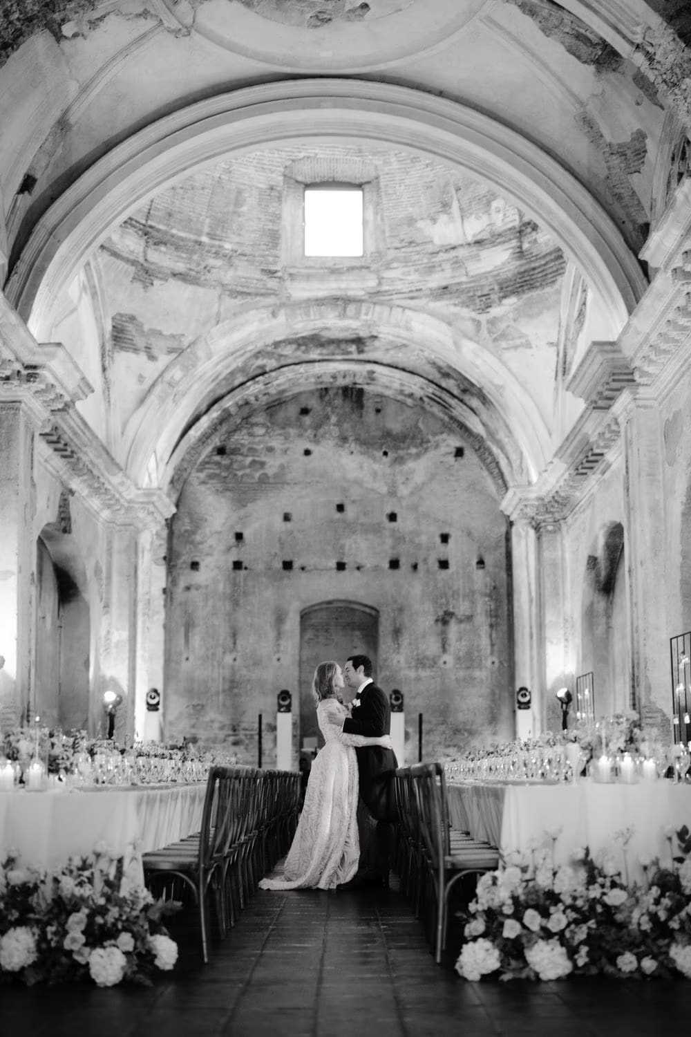 Close-up of a reception table dressed with peach and ivory florals by Cynthia Carrillo, gold place settings and candles inside the ruins — Antigua Guatemala wedding.
