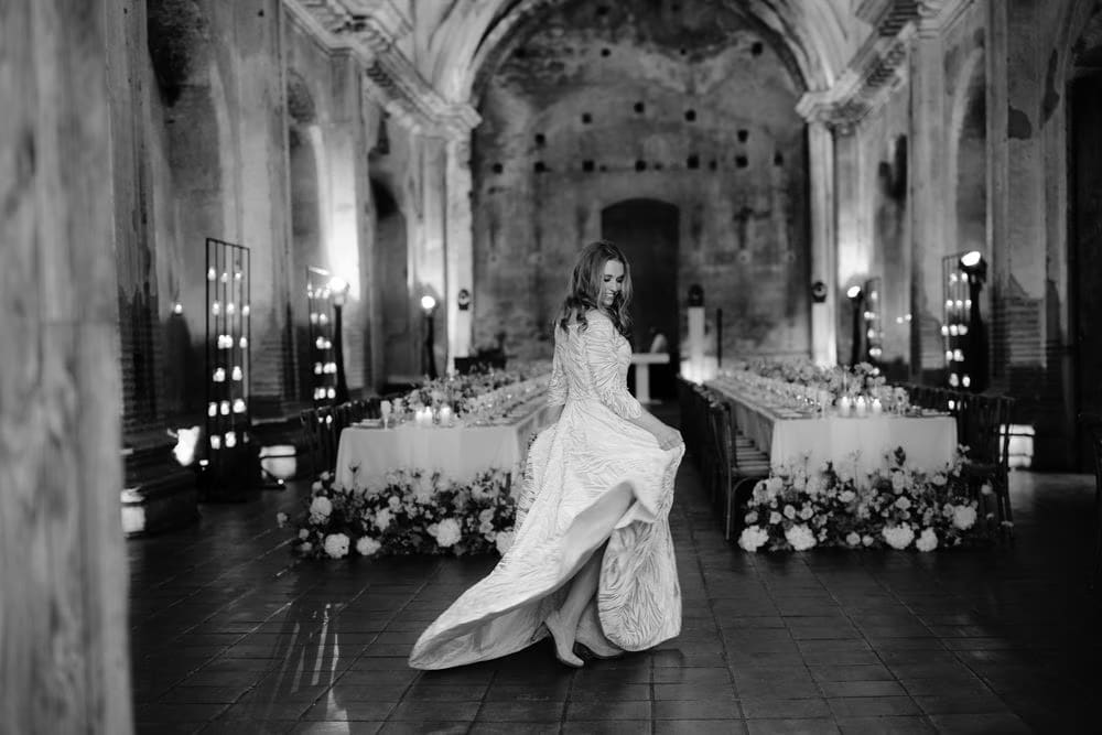 Black-and-white moment of the bride lifting her gown mid-spin inside the ruins — colonial Antigua wedding.