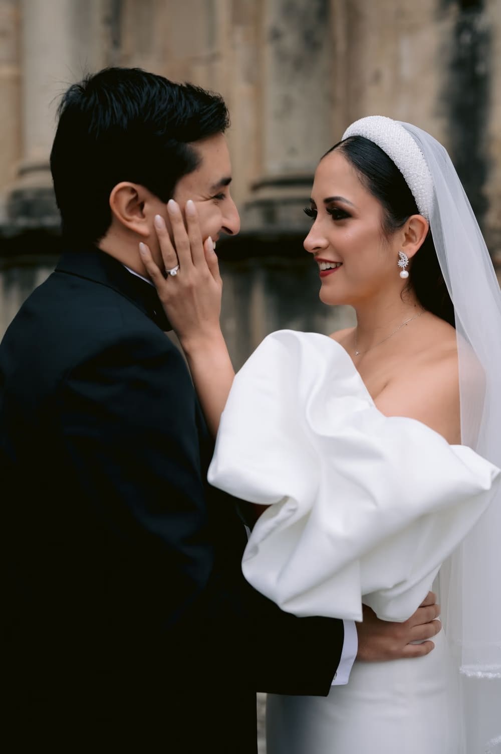 Bride cradles the groom's face as they share a tender moment outside the convent ruins in Antigua Guatemala.