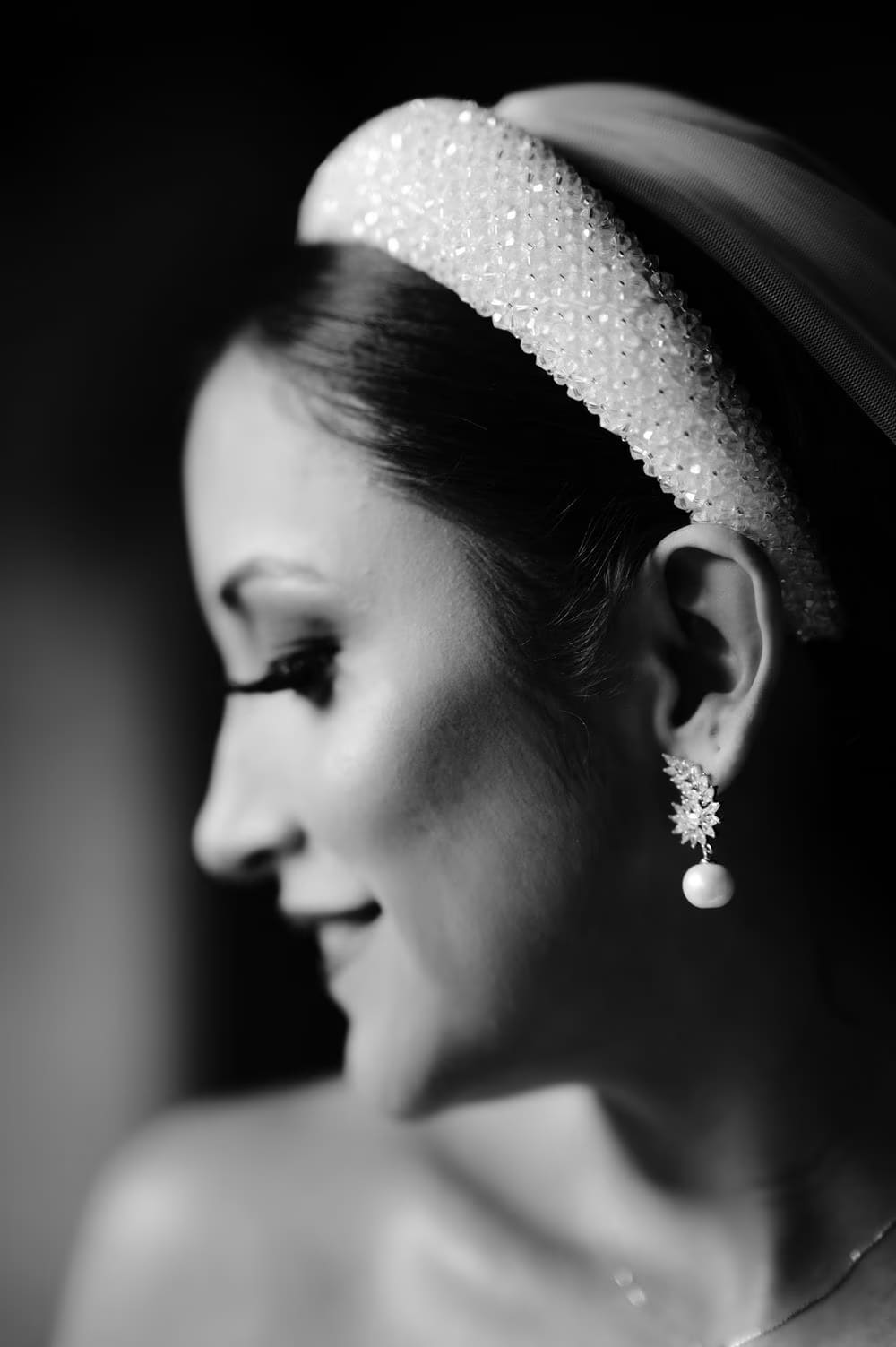 Black-and-white profile of bride with beaded headband and pearl earring catching the light.