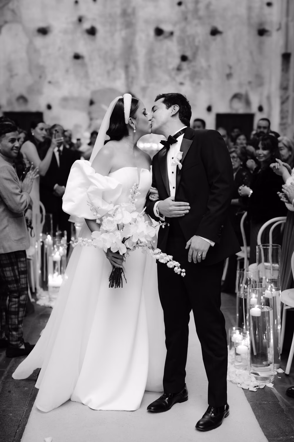First kiss — bride and groom seal the ceremony with a kiss in front of an applauding crowd of guests.