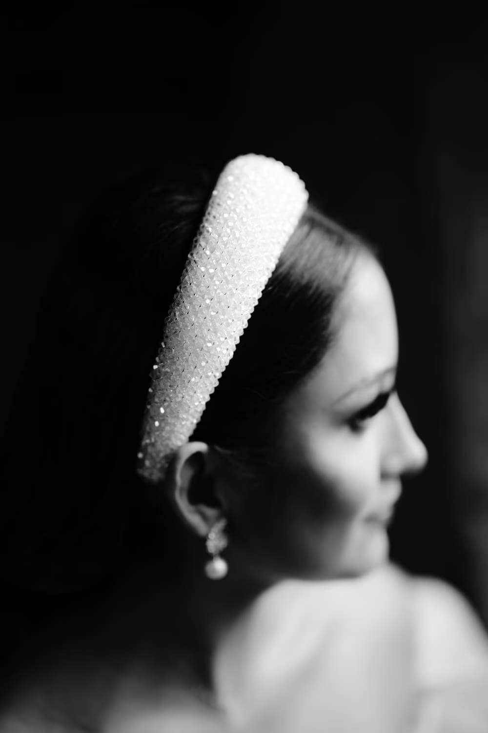 Detail of the crystal-beaded bridal headband and pearl drop earring in dramatic black-and-white profile.