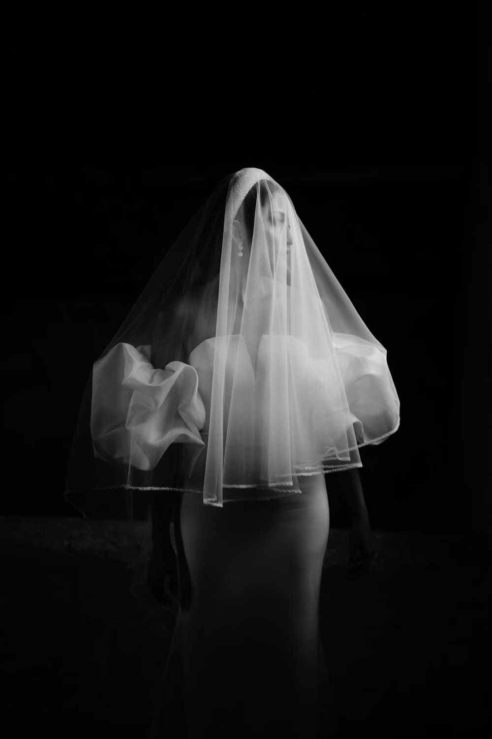 Bride seen through a sheer veil draped completely over her face and gown — fine-art bridal portrait.
