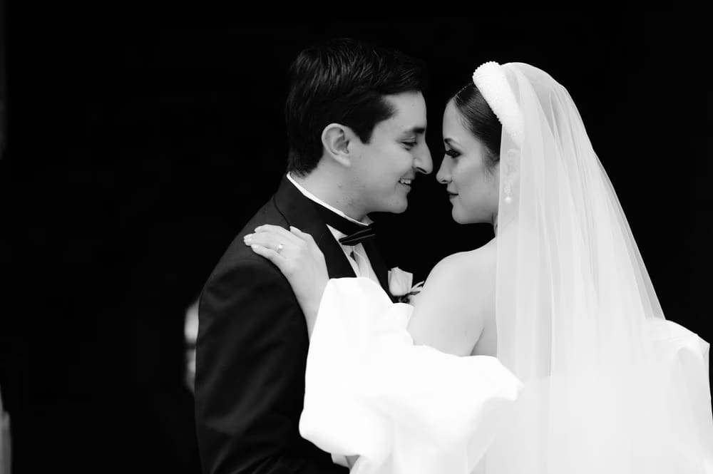Foreheads pressed together, bride and groom share a quiet moment in black-and-white.
