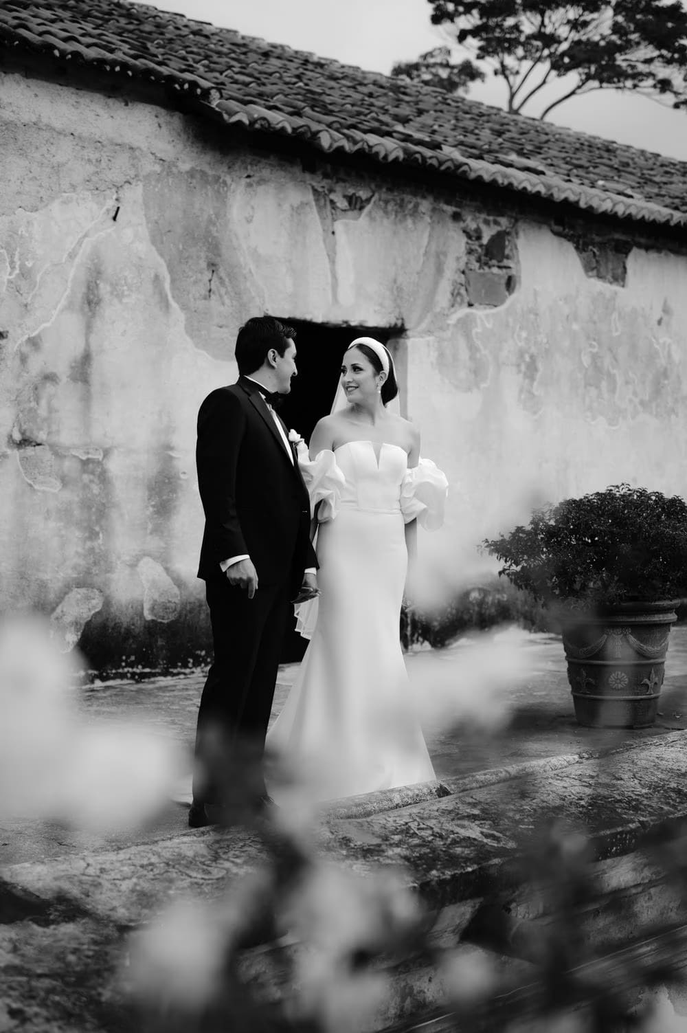 Black-and-white portrait of the couple in front of a textured stucco wall on the cloister rooftop.
