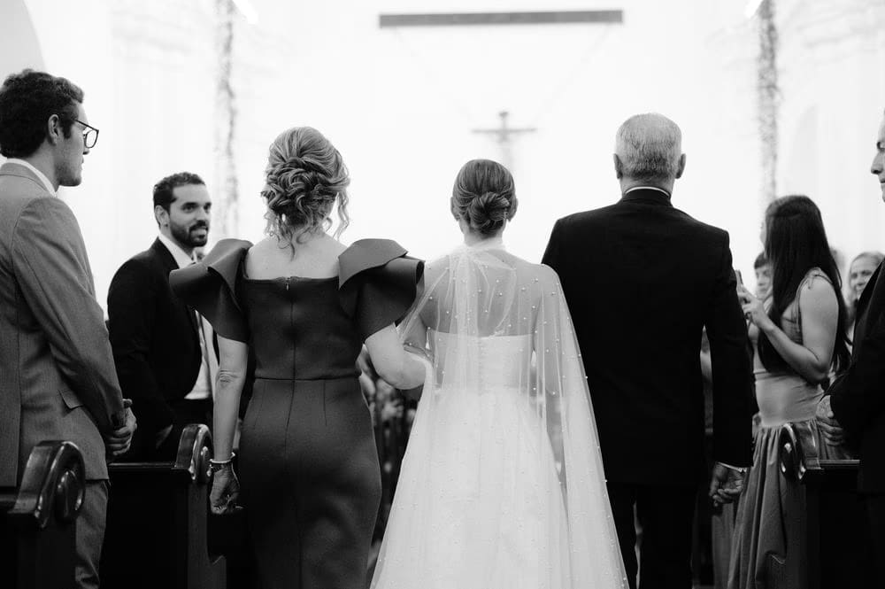 Black-and-white view from behind as bride and her parents reach the altar — destination wedding ceremony in Antigua Guatemala.