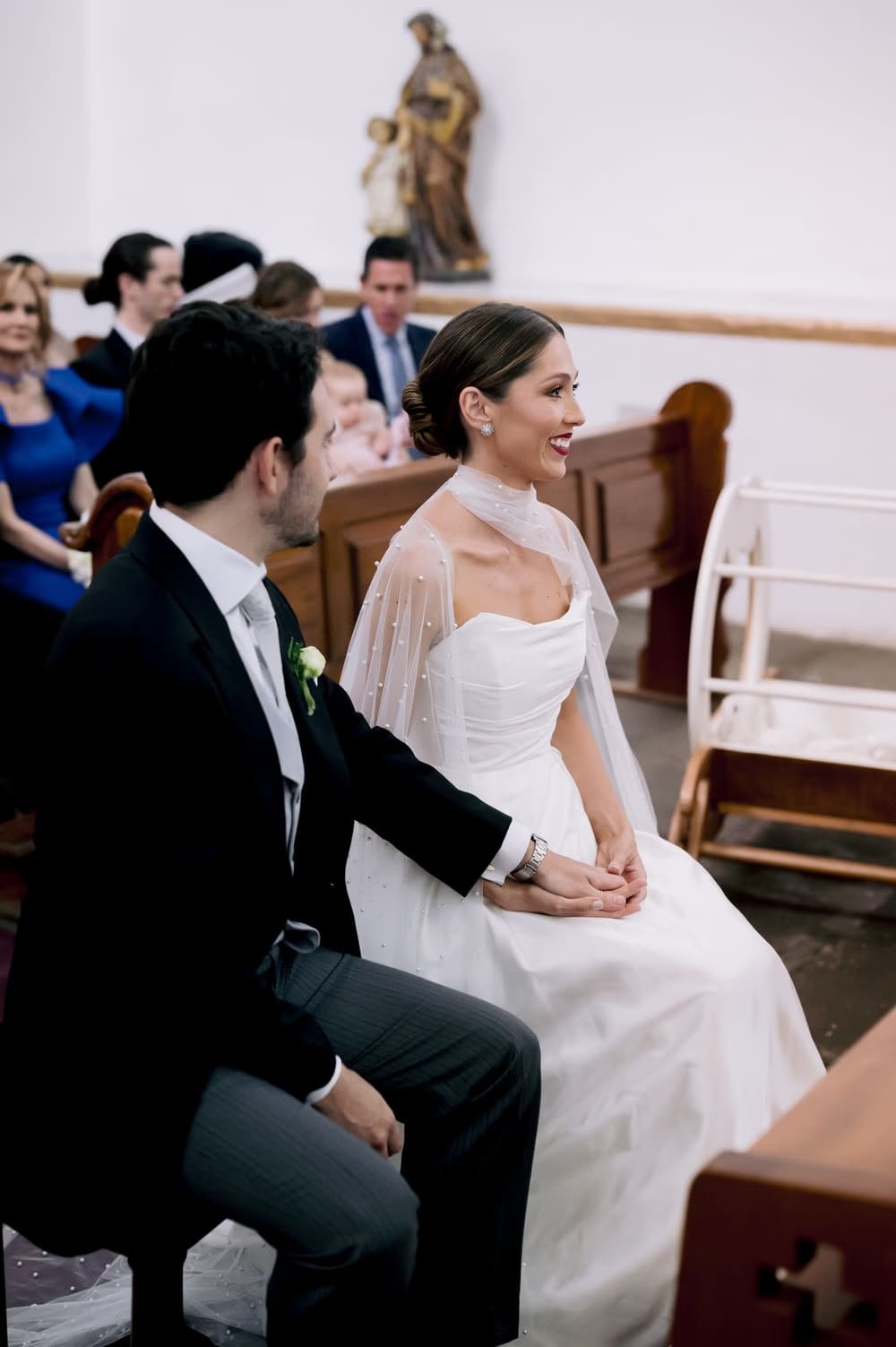 Bride laughs softly seated beside the groom in the church pew during the ceremony in Antigua Guatemala.