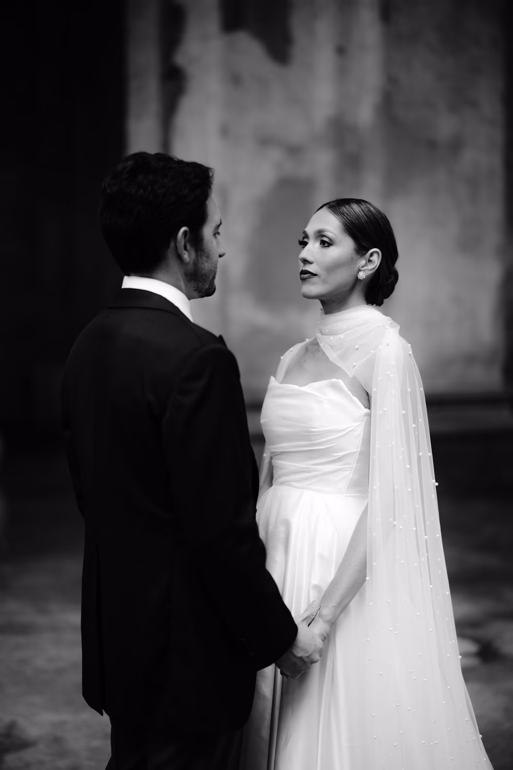 Black-and-white portrait of bride and groom holding hands inside Capuchinas Ruins — editorial destination wedding moment.
