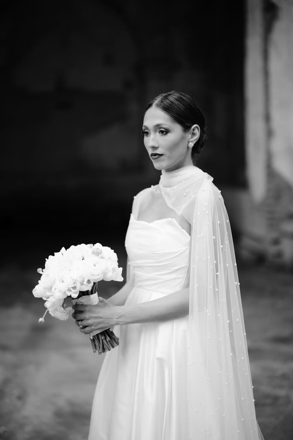 Black-and-white close portrait of the bride holding her white bouquet inside the cloister — Capuchinas Ruins wedding.