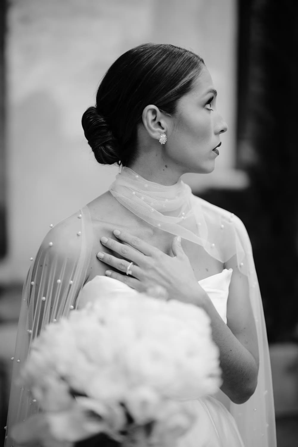 Black-and-white profile of the bride showing her low bun, diamond stud and hand resting at her chest in colonial Antigua.