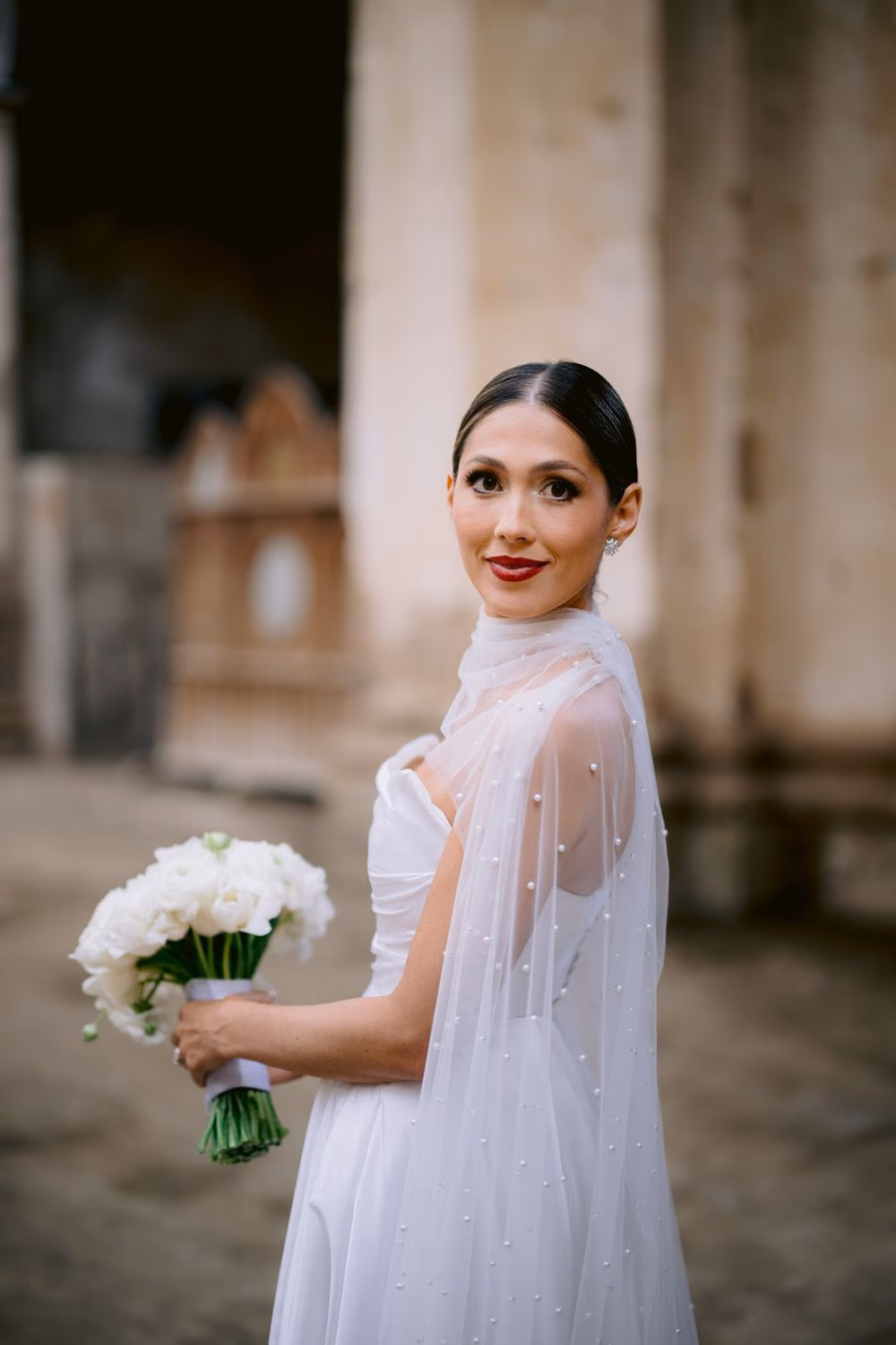 Bride pauses with her bouquet in a quiet corridor at Capuchinas Ruins — editorial portrait in La Antigua.