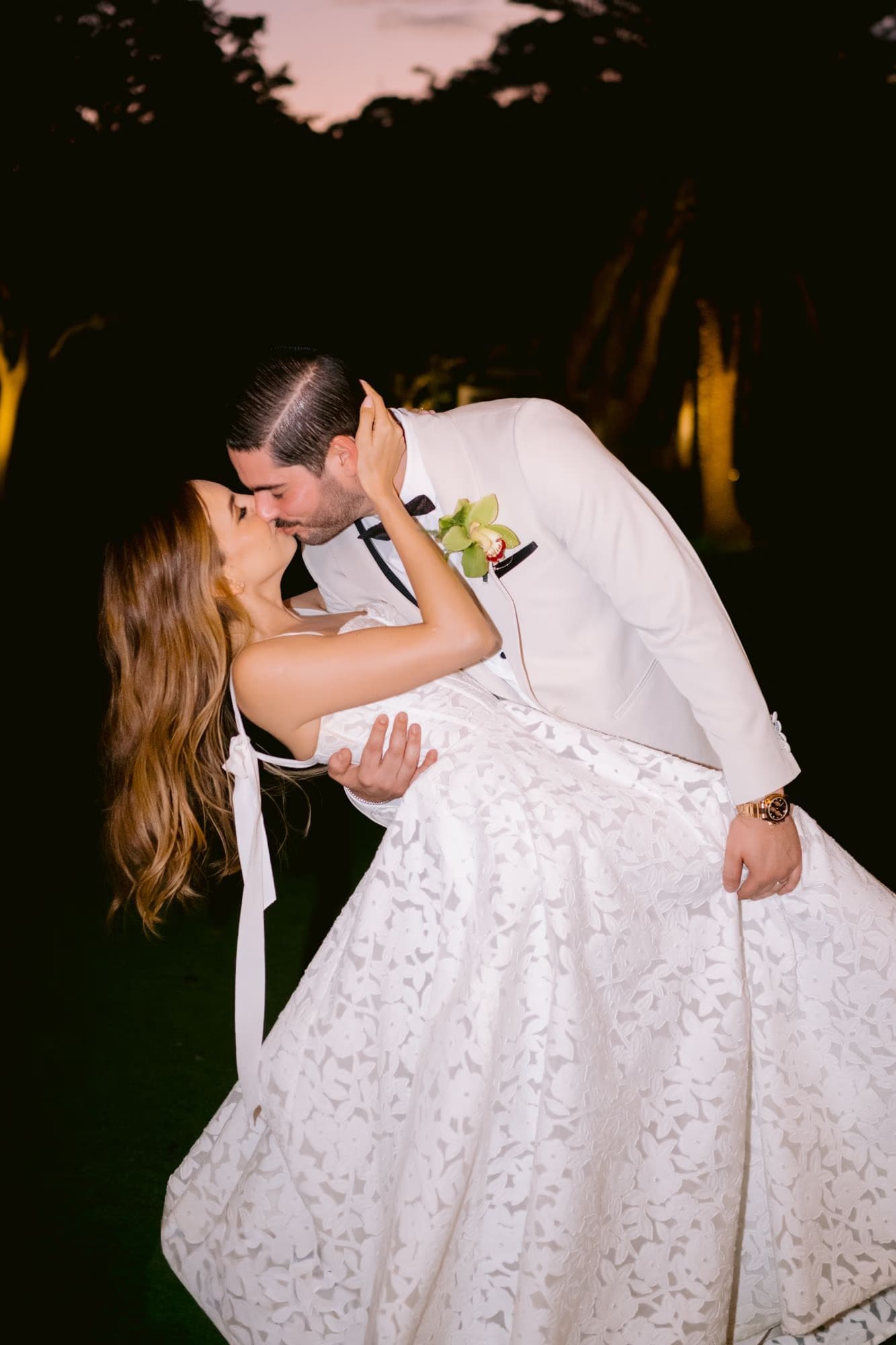 Bride in lace ball gown dipped into a kiss under garden trees at Villa Bokeh — destination wedding in Antigua Guatemala.
