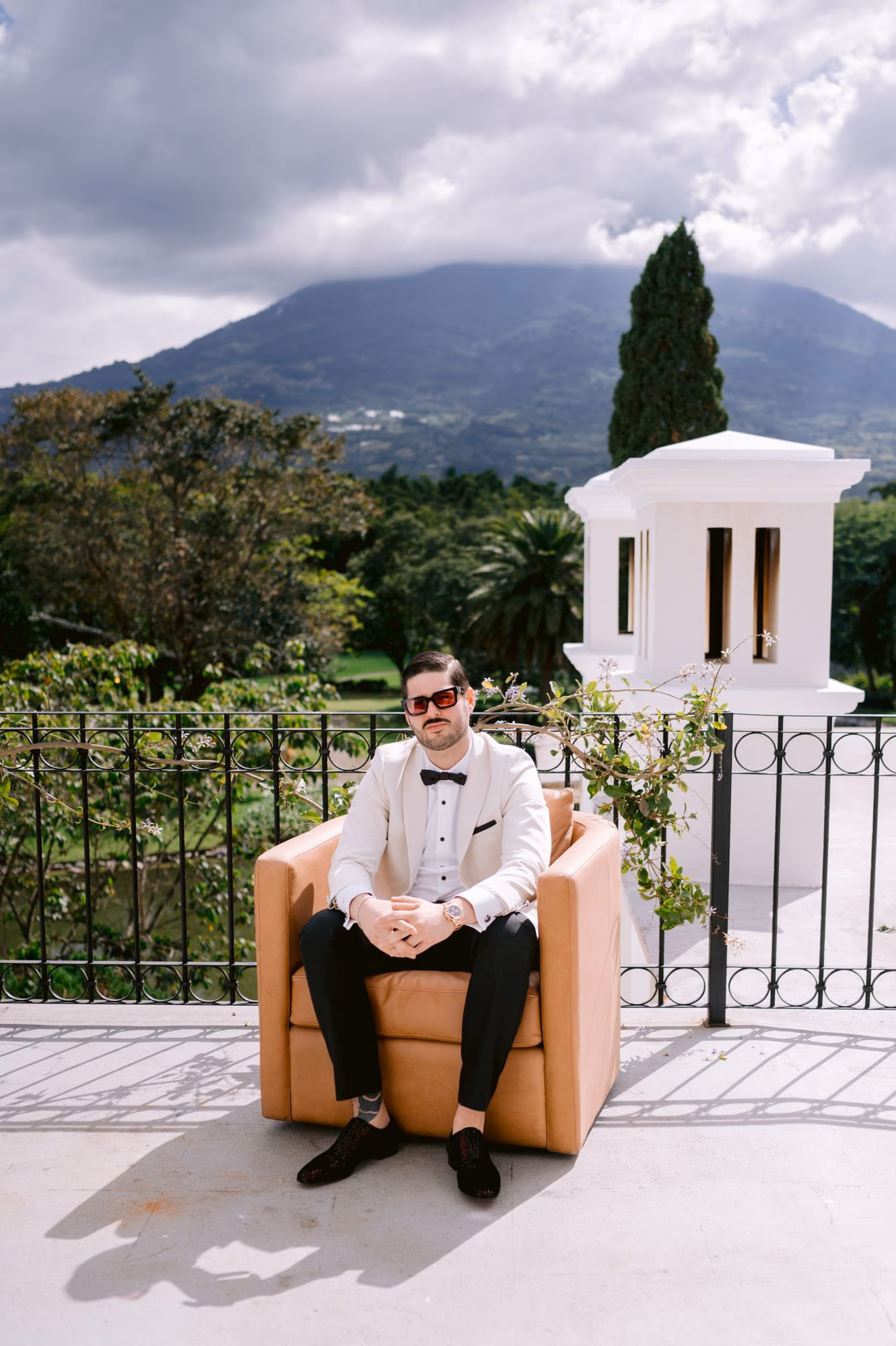 Sergio seated alone in a tan armchair on a terrace with volcano views in Antigua Guatemala.