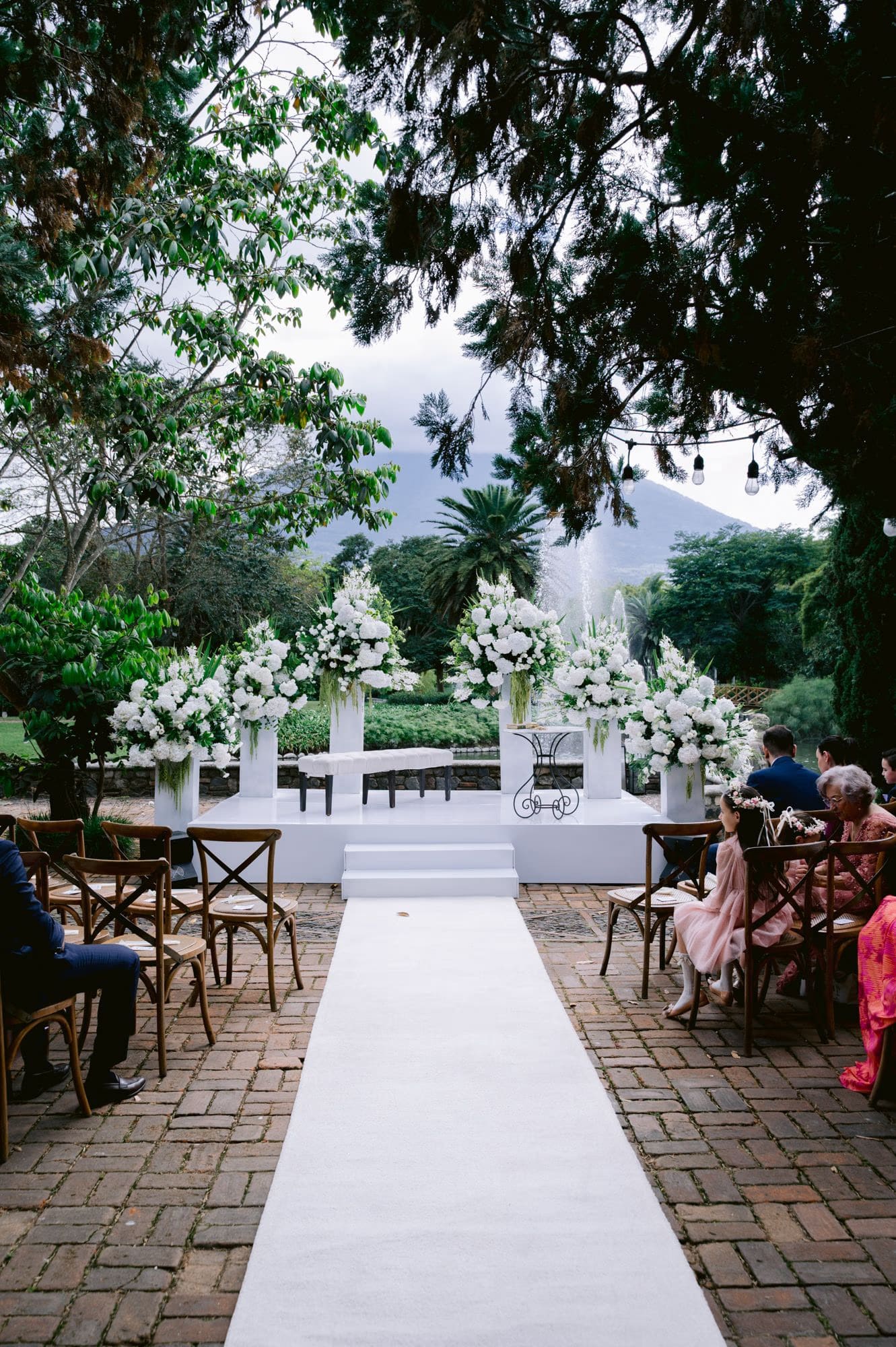 Ceremony aisle framed by white floral pillars and volcano view at Villa Bokeh, La Antigua.