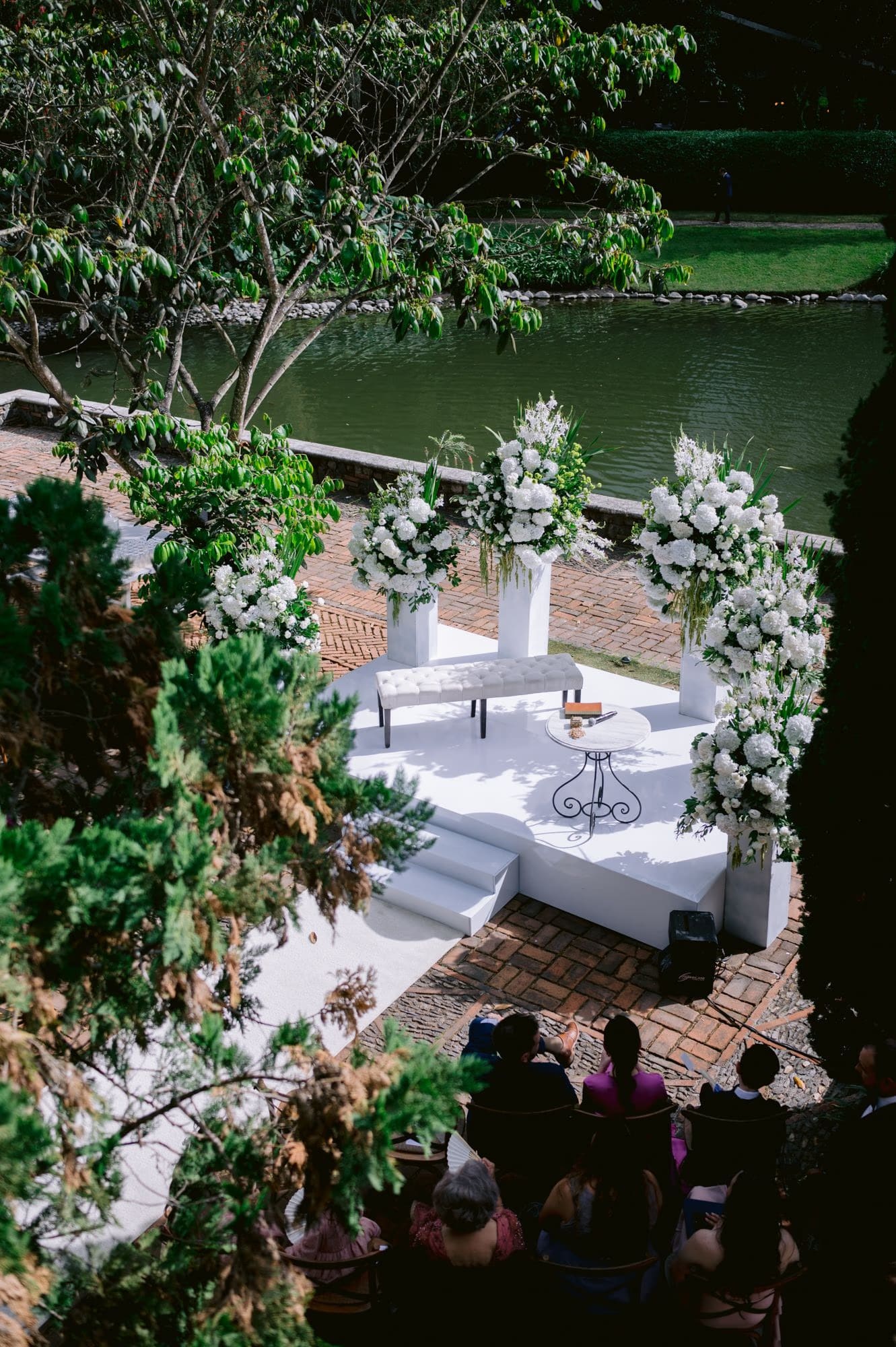 Floral altar overlooking the lagoon, guests seated below — garden wedding ceremony in Antigua.