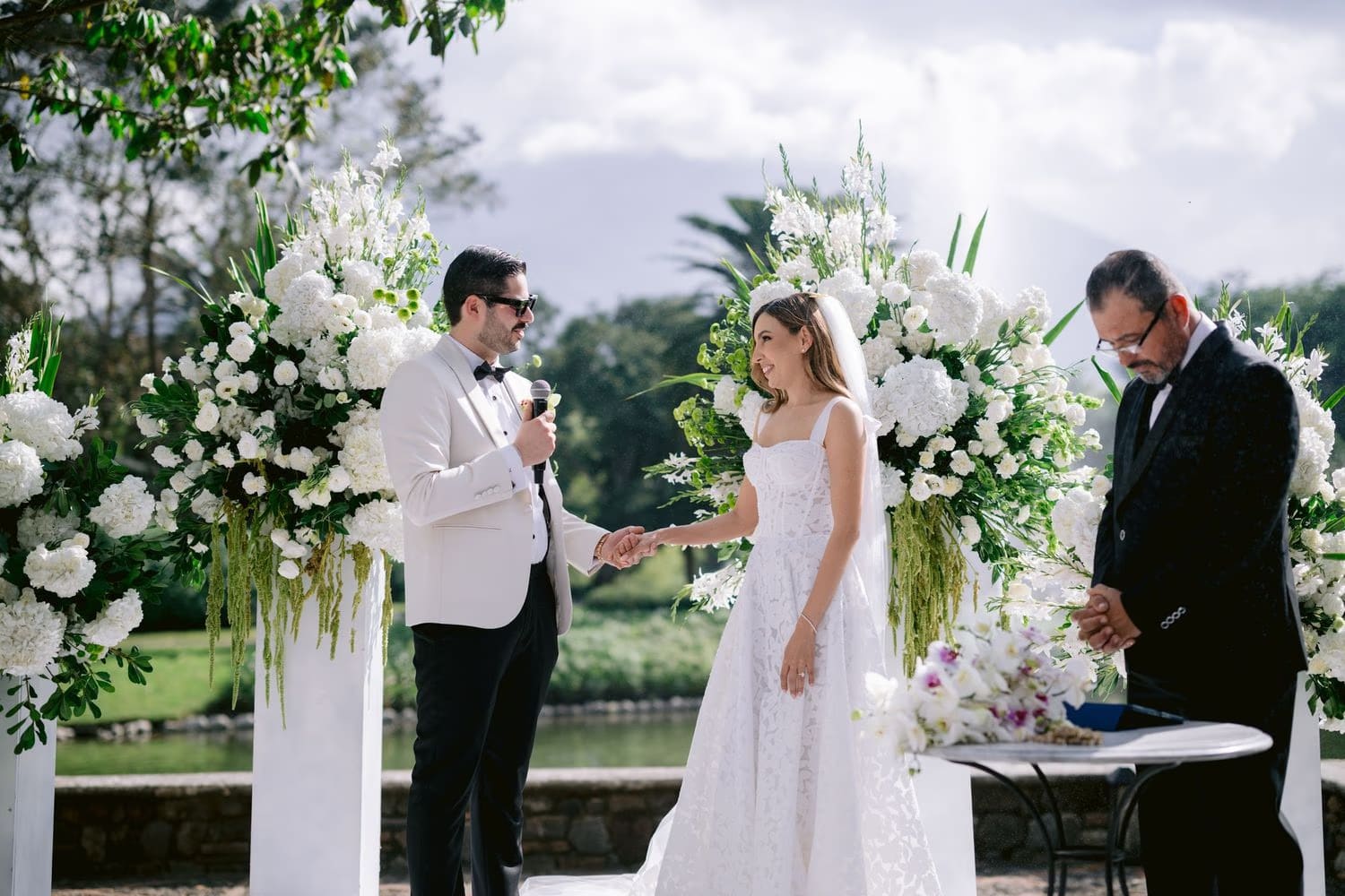 Sergio speaks his vows holding Caro's hand at the floral altar — ceremony in La Antigua Guatemala.
