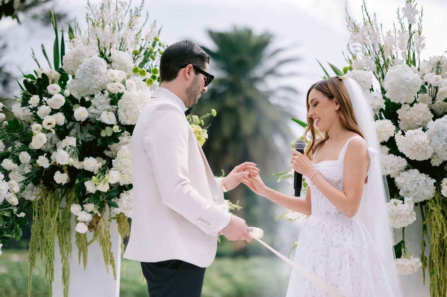 Caro reads her vows on the microphone while Sergio slides on her ring — wedding ceremony in Antigua Guatemala.