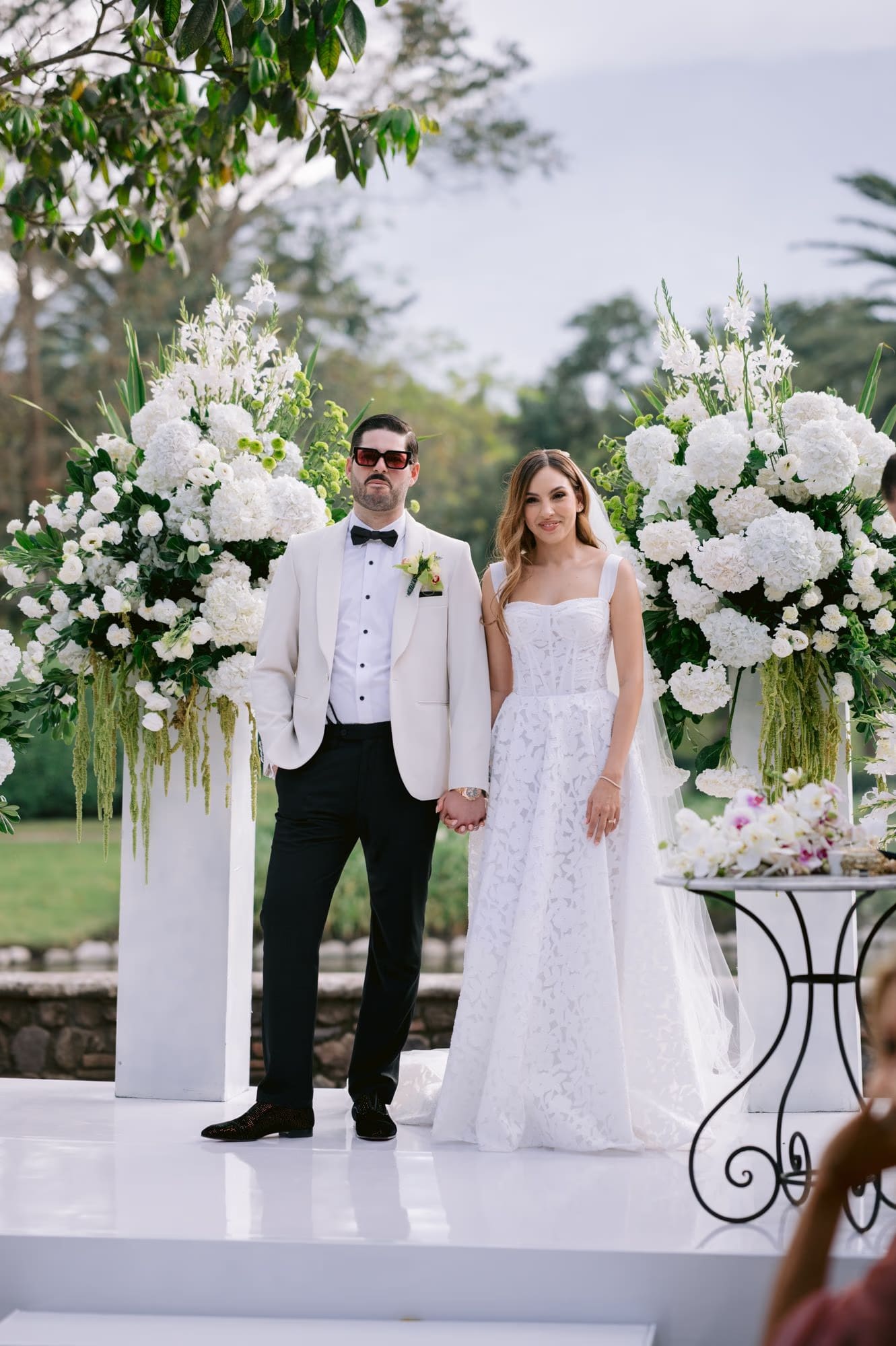 Bride and groom stand framed by towering white florals during their ceremony at La Antigua Guatemala.