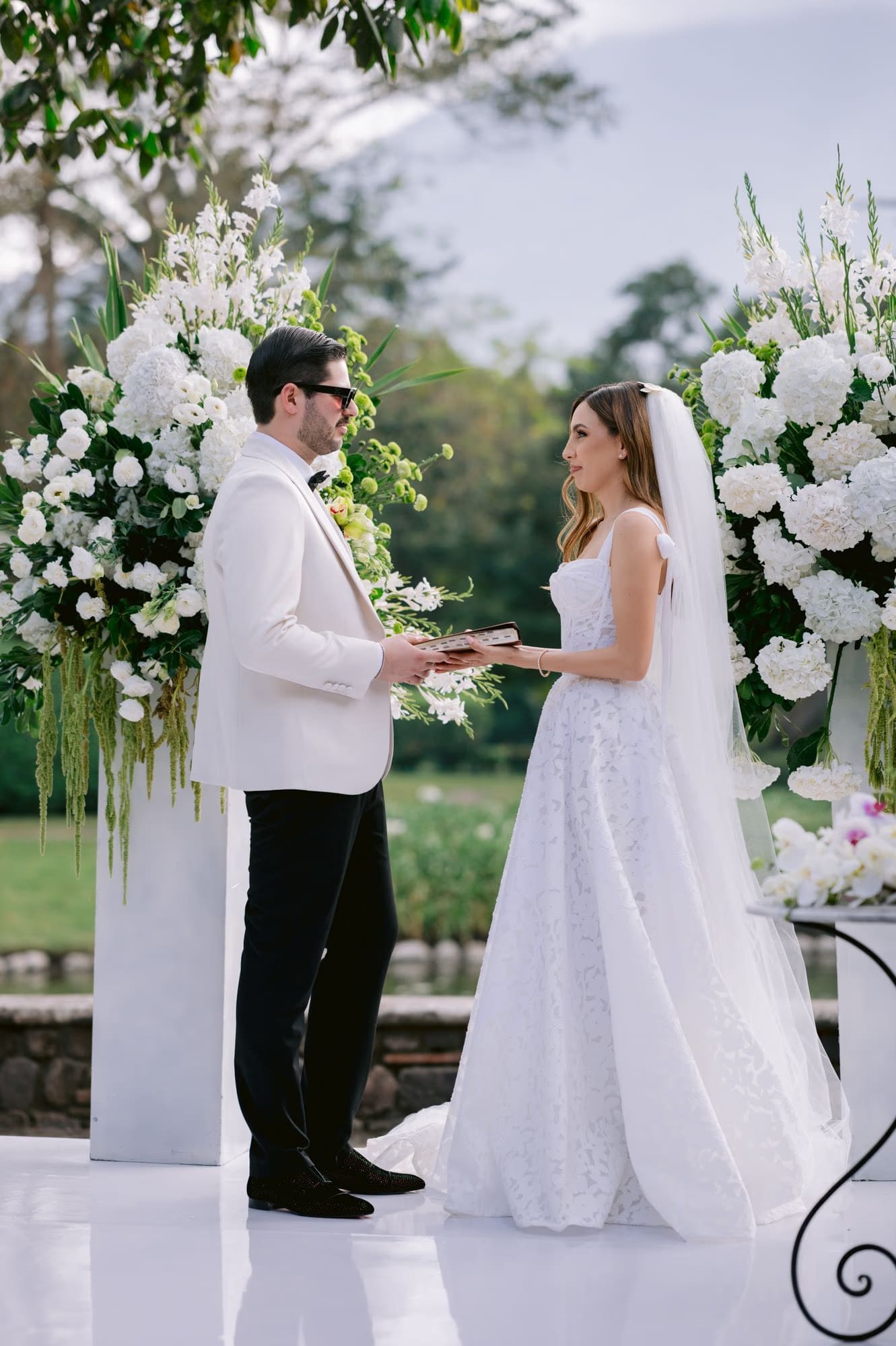 Sergio reads from a leather vow book while Caro listens at the altar — intimate ceremony moment.