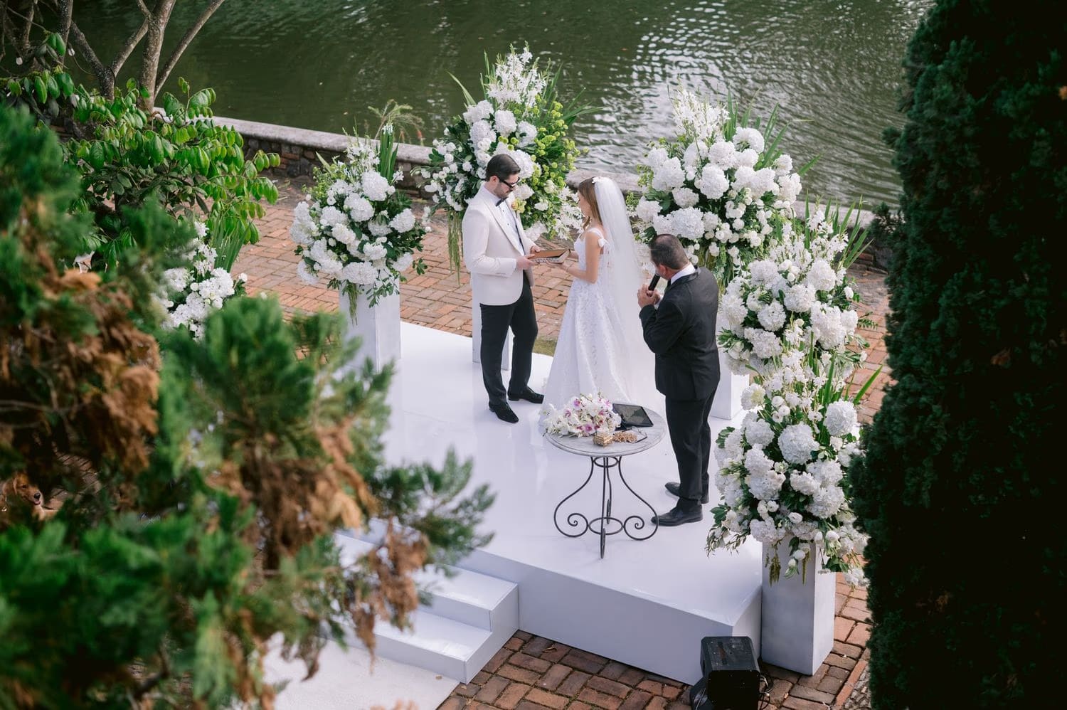 Overhead shot of the ceremony altar with officiant kneeling beside the couple — garden wedding in Antigua.