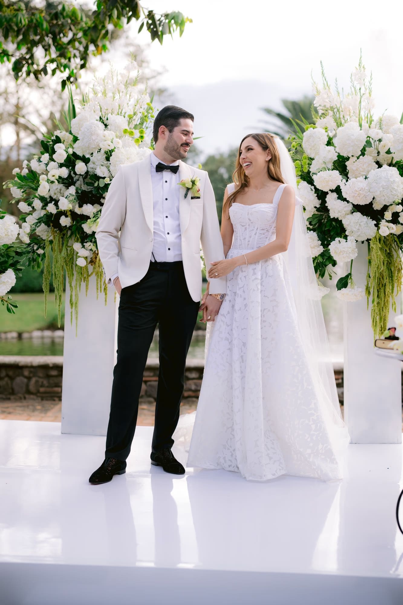 Bride and groom share a laughing look at the altar — relaxed ceremony moment at Villa Bokeh.
