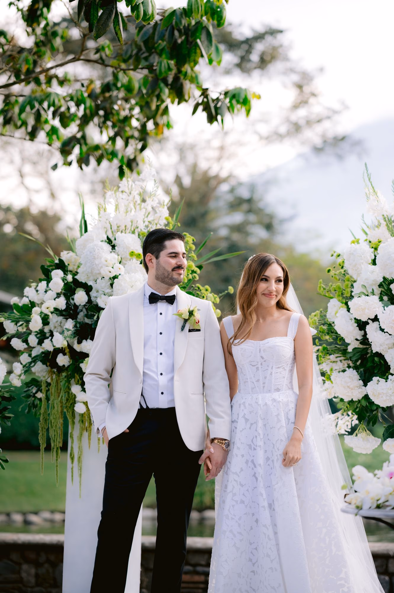 Newlywed portrait under an arched canopy of greenery and white florals at La Antigua.