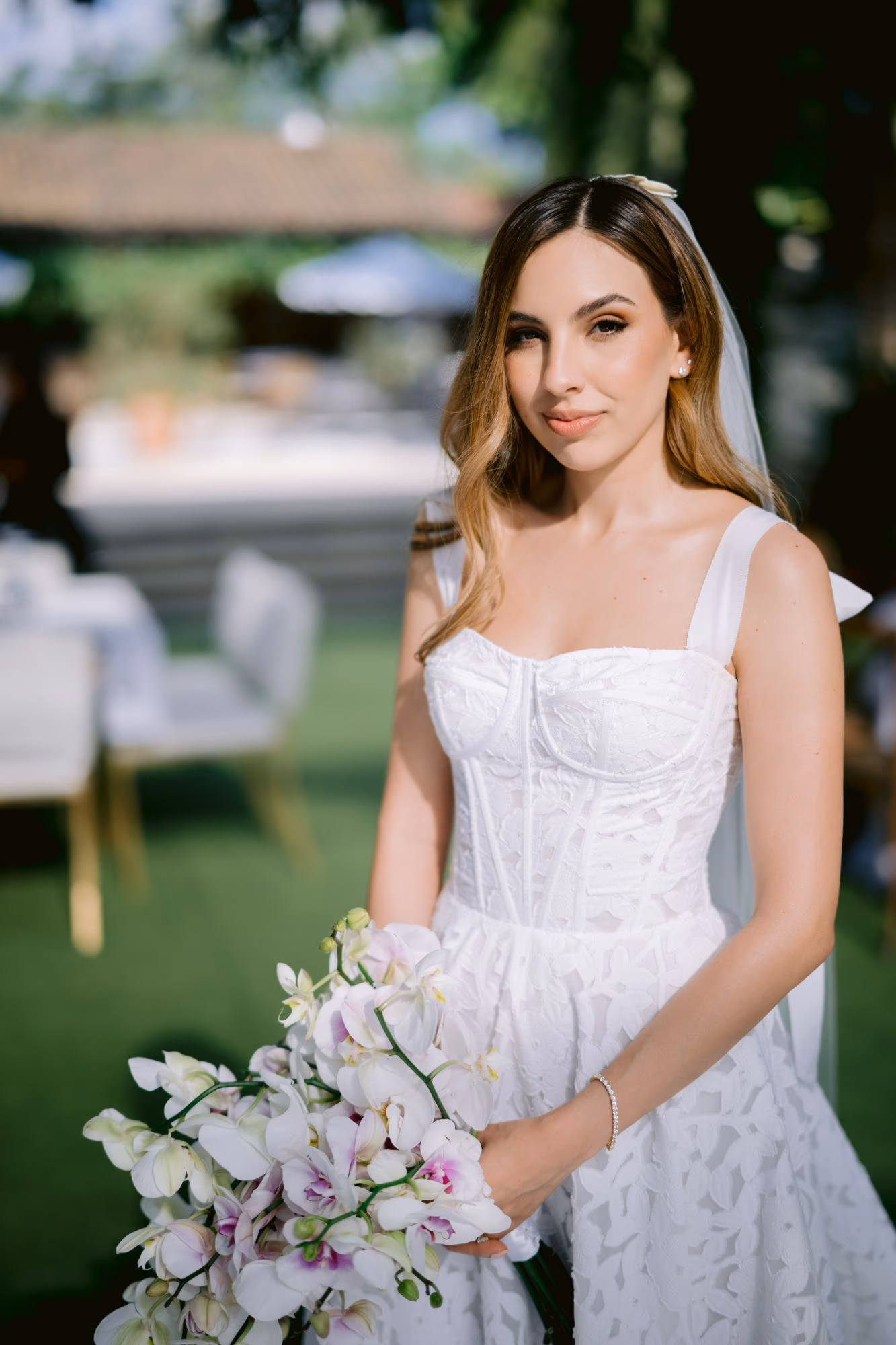 Soft bridal portrait of Caro holding her orchid bouquet under garden shade.