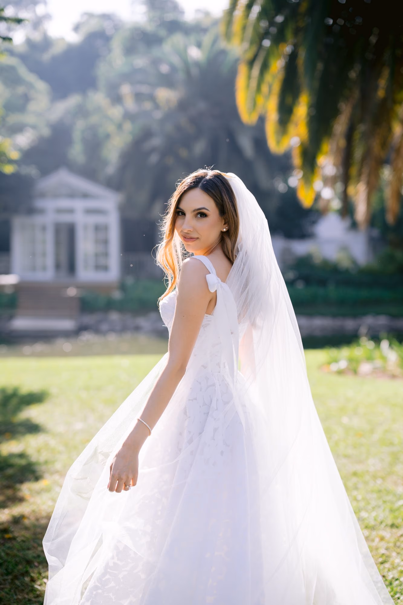 Caro turns in golden light with her veil sweeping behind in the gardens of Villa Bokeh.