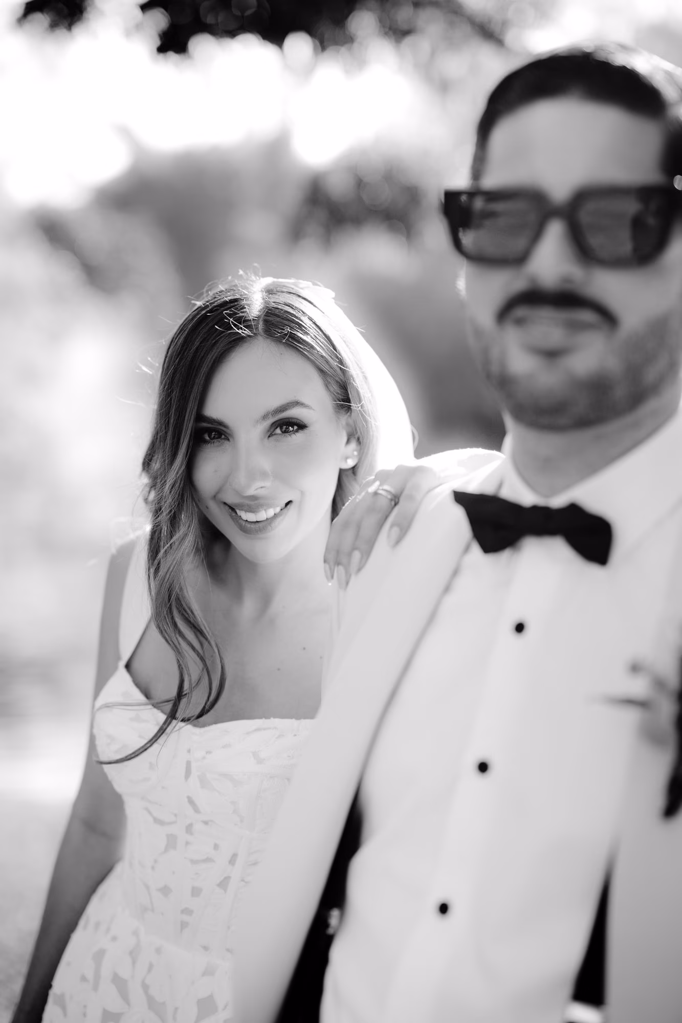 Black-and-white close-up of bride leaning on the groom's shoulder, both smiling softly.