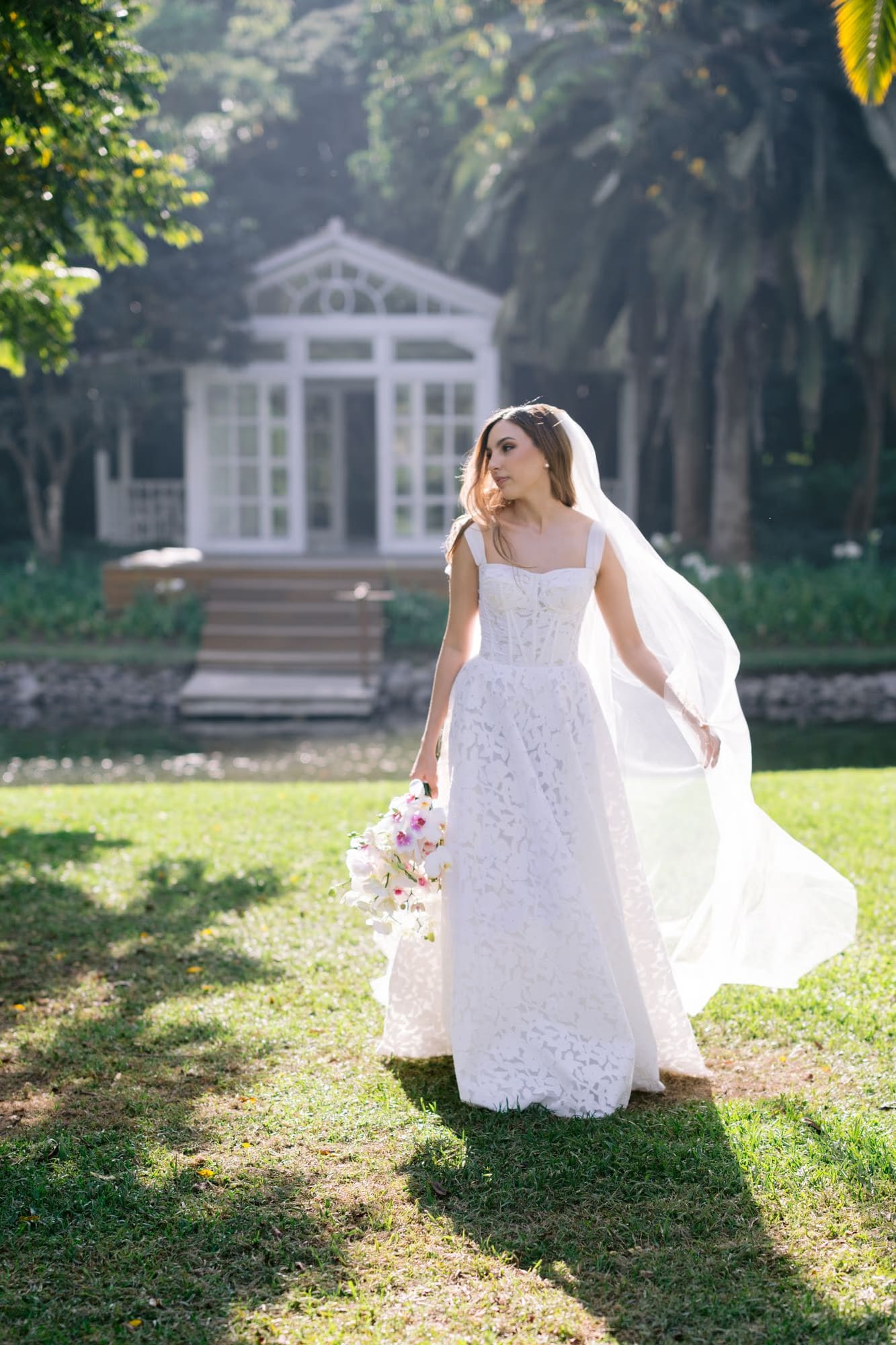 Bride poses solo in front of the white garden house at Villa Bokeh — golden hour bridal portrait.