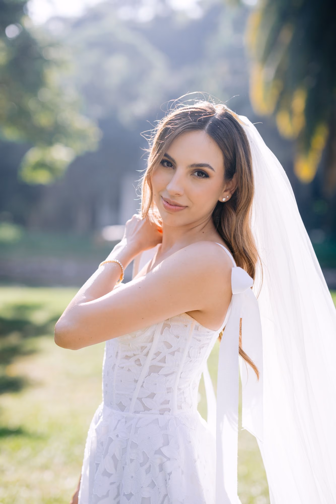 Bridal portrait of Caro in soft afternoon light, hand brushing her hair beside her veil.