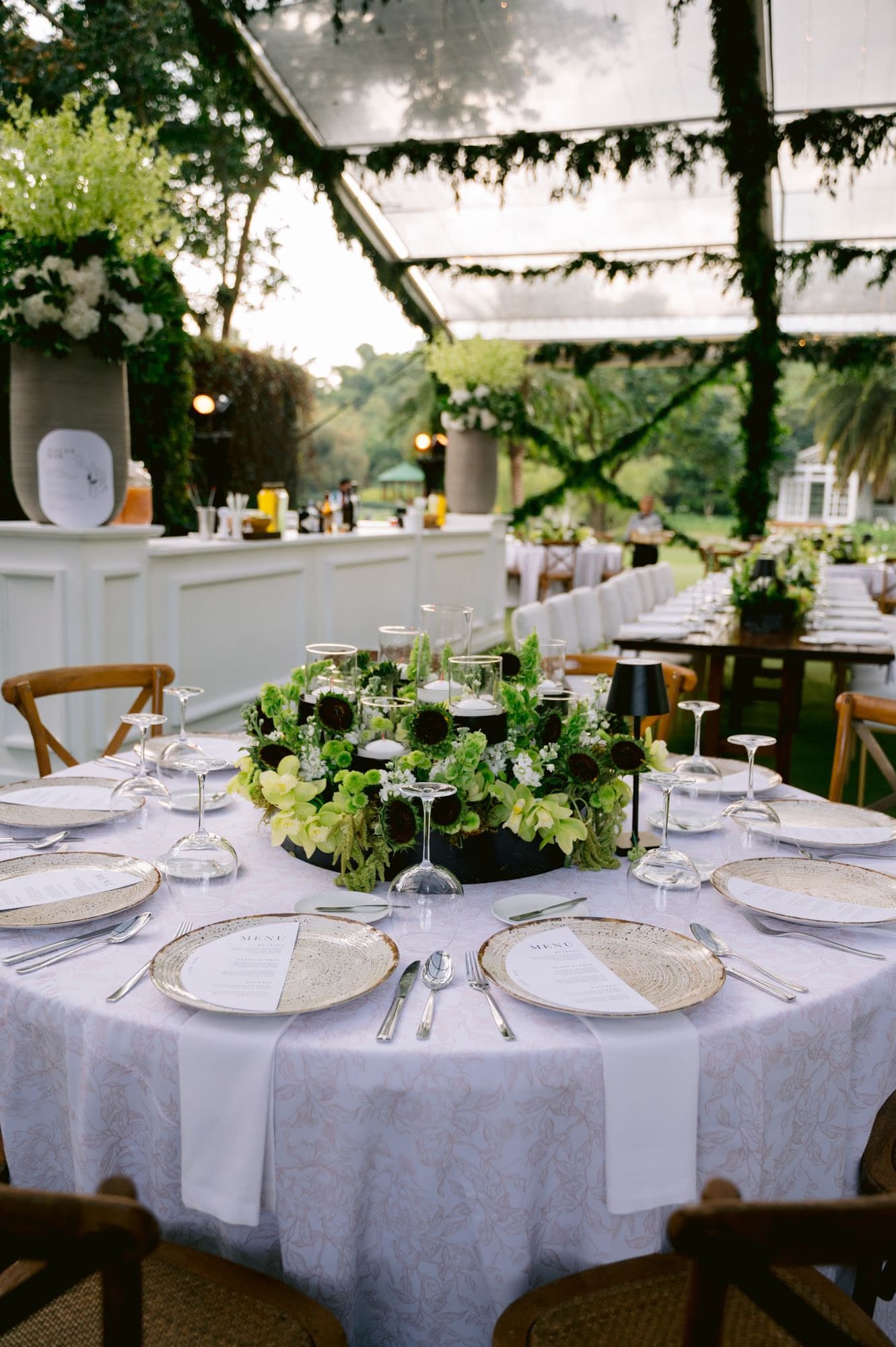 Reception round table set with greenery centerpiece under the clear tent at Villa Bokeh.