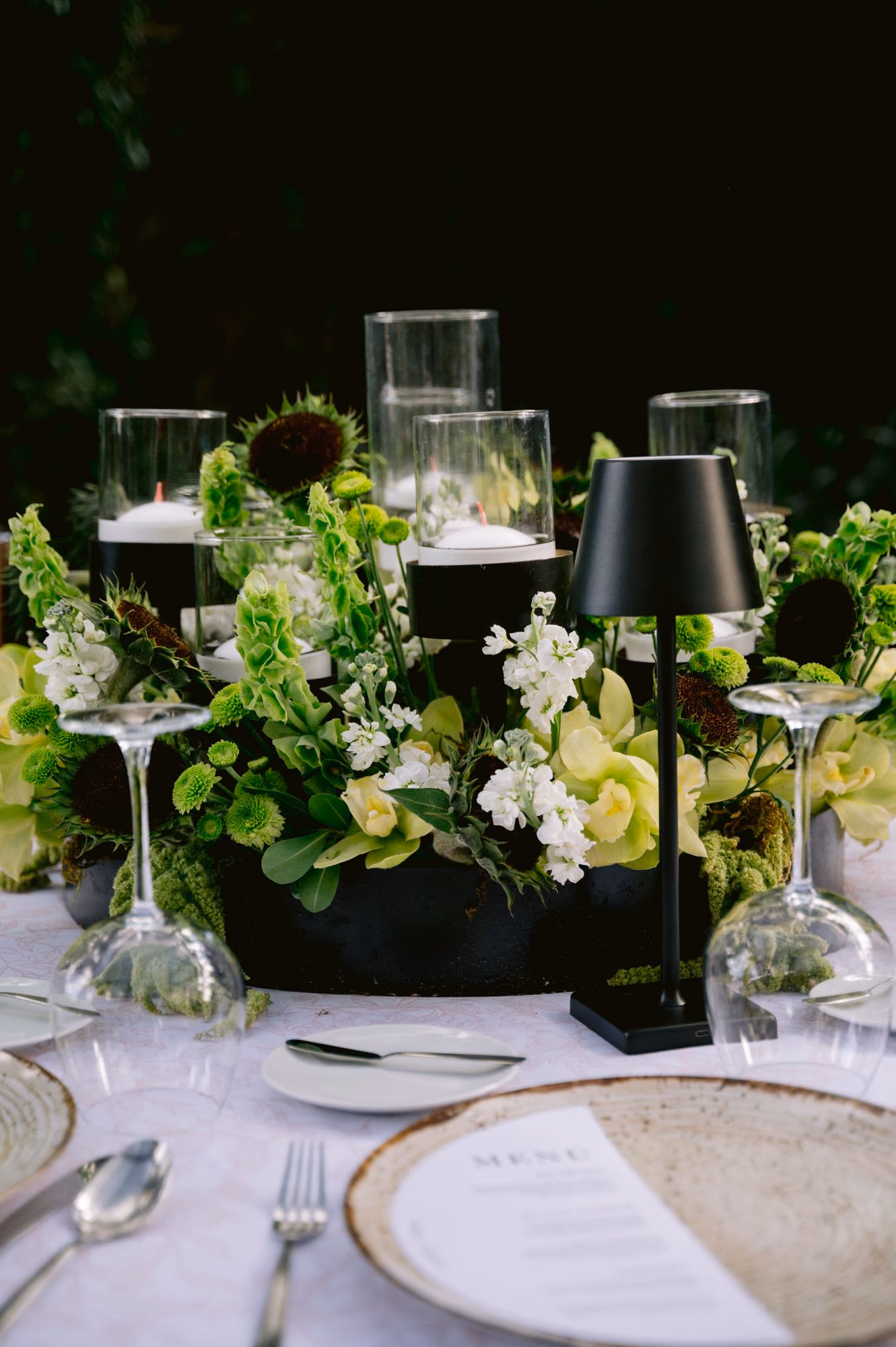 Reception centerpiece detail with green orchids, white stock and floating candles — Antigua wedding decor.