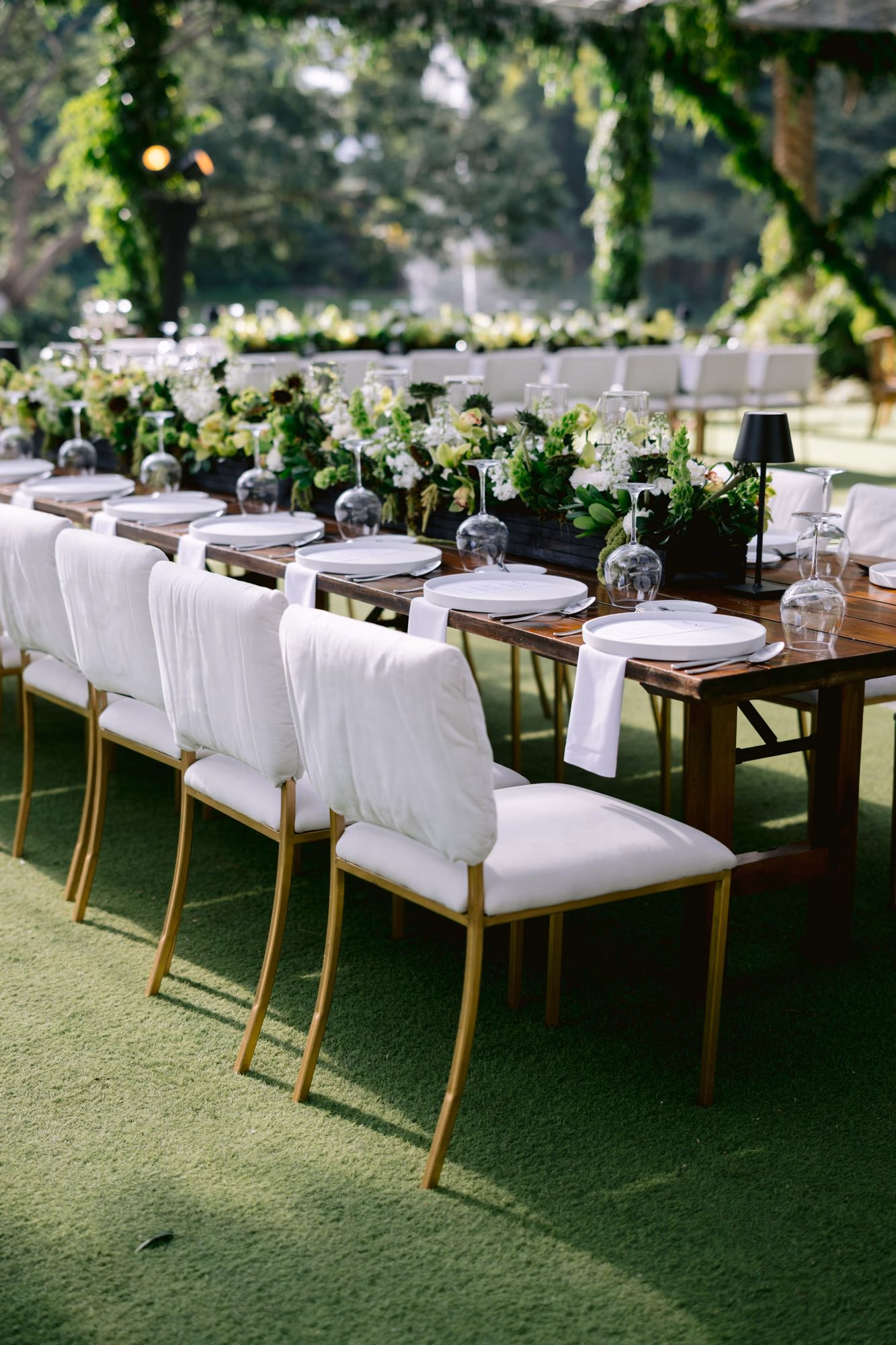 Row of upholstered chairs along a long wooden reception table with green centerpieces — Antigua Guatemala wedding.