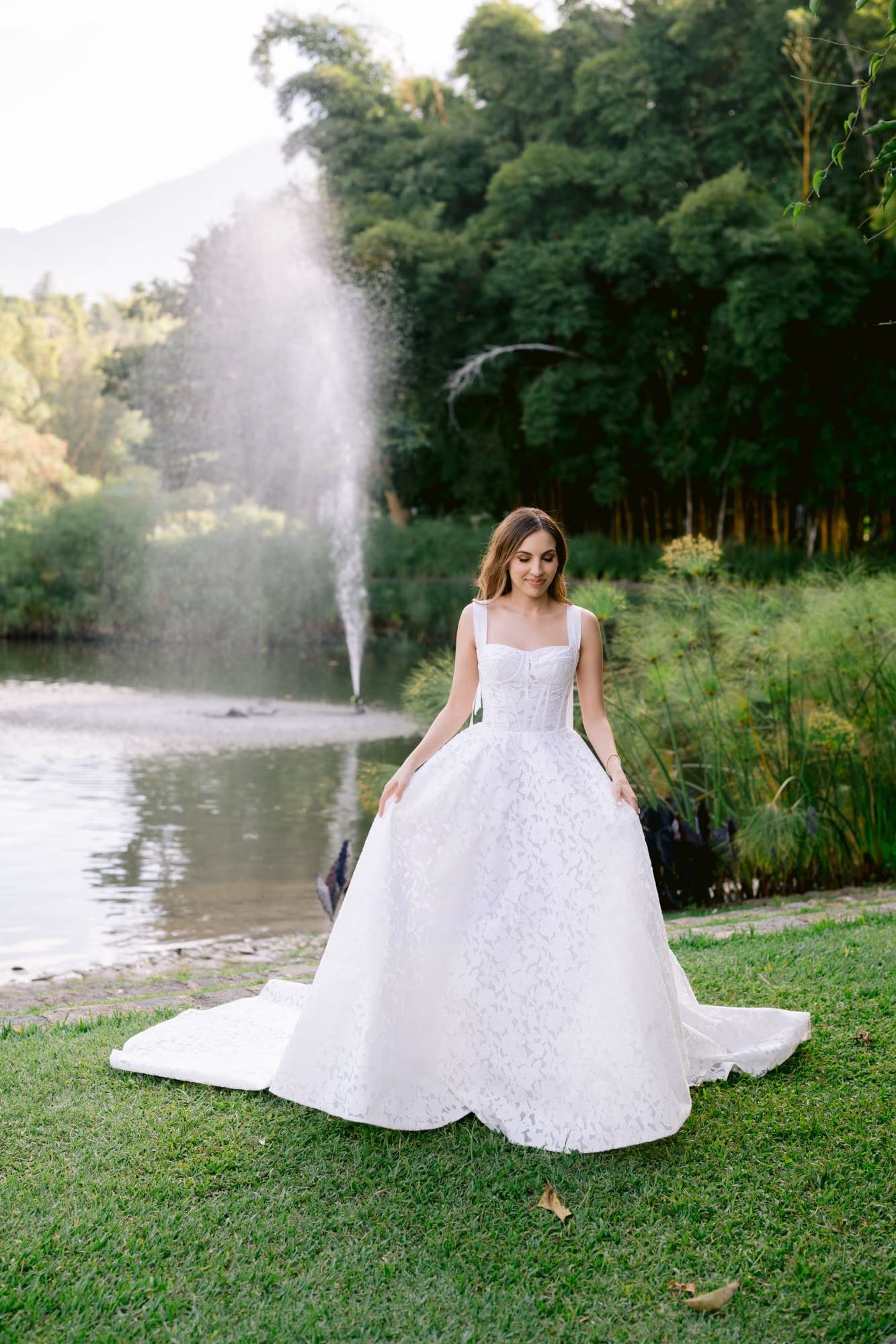Bride twirls in her ball gown beside the lagoon fountain, black swan floating nearby at La Antigua.