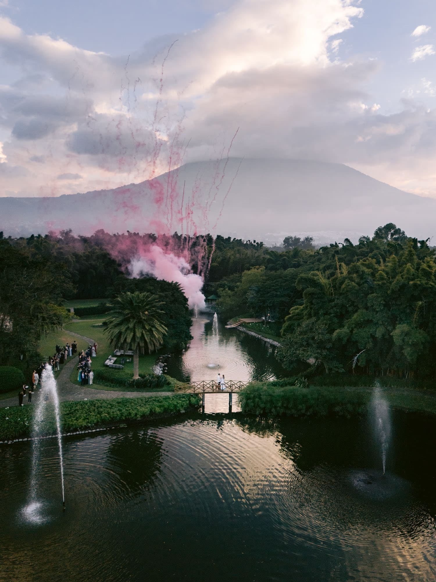 Aerial fireworks burst above the volcano as the couple stands on the bridge at Villa Bokeh — destination wedding in Antigua Guatemala.