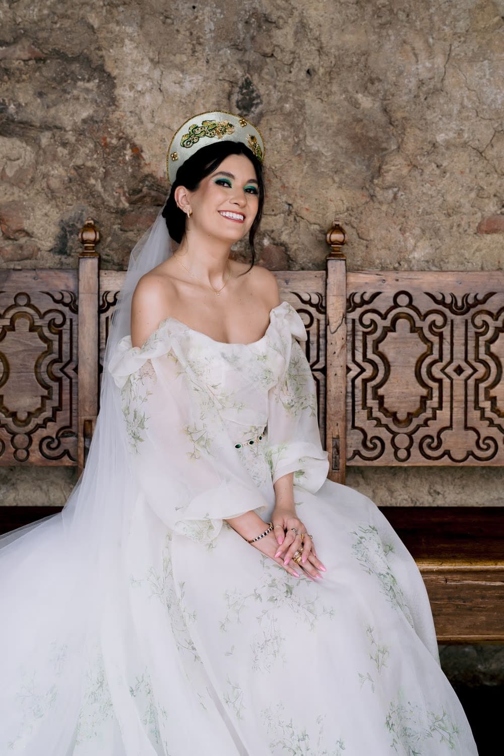Bride sits laughing on a carved wooden bench inside a candle-lit stone vault at Hotel Casa Santo Domingo, Antigua Guatemala.