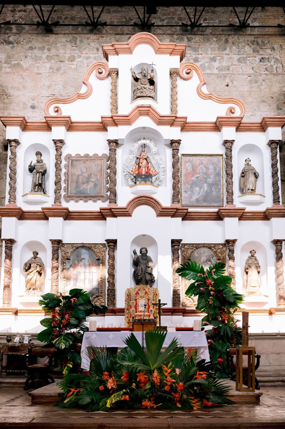Baroque chapel altarpiece flanked by tropical floral arrangements ready for the wedding ceremony.